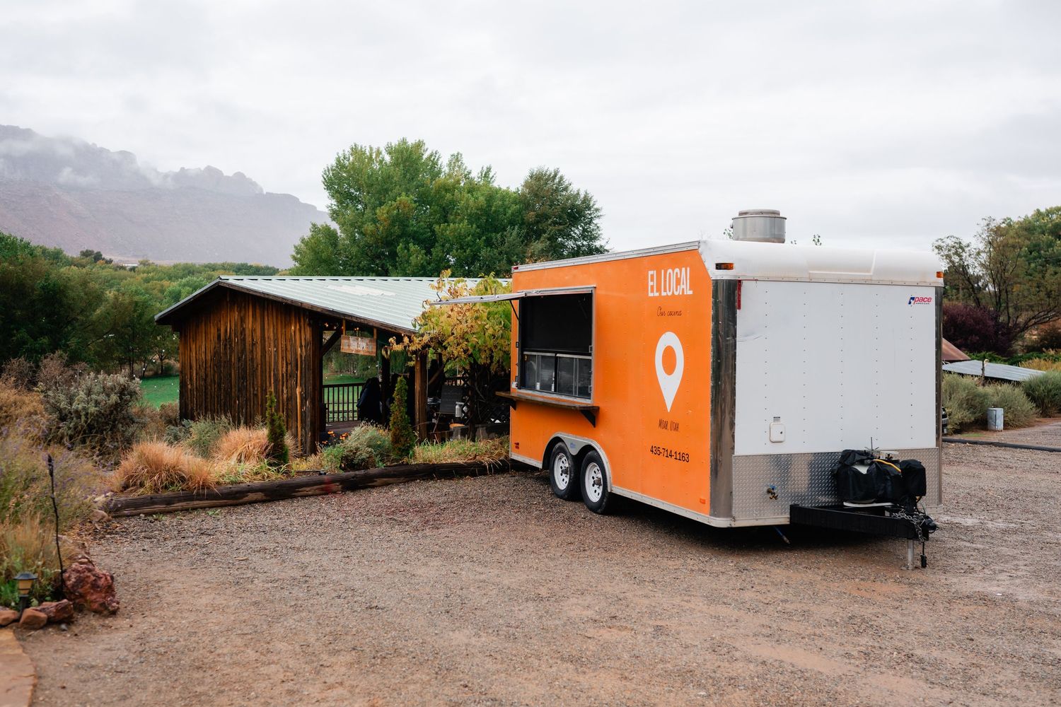 Food trucks and trailers parked in a desert landscape with mountains in the background.