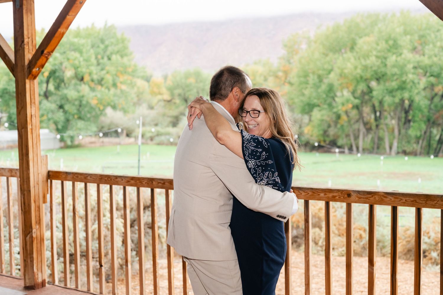Couple embracing during dance on wooden deck with mountain scenery in background.