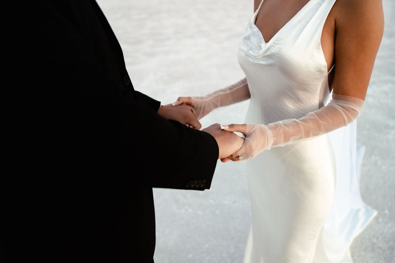Close-up details of wedding dress and hands during intimate ceremony moments.