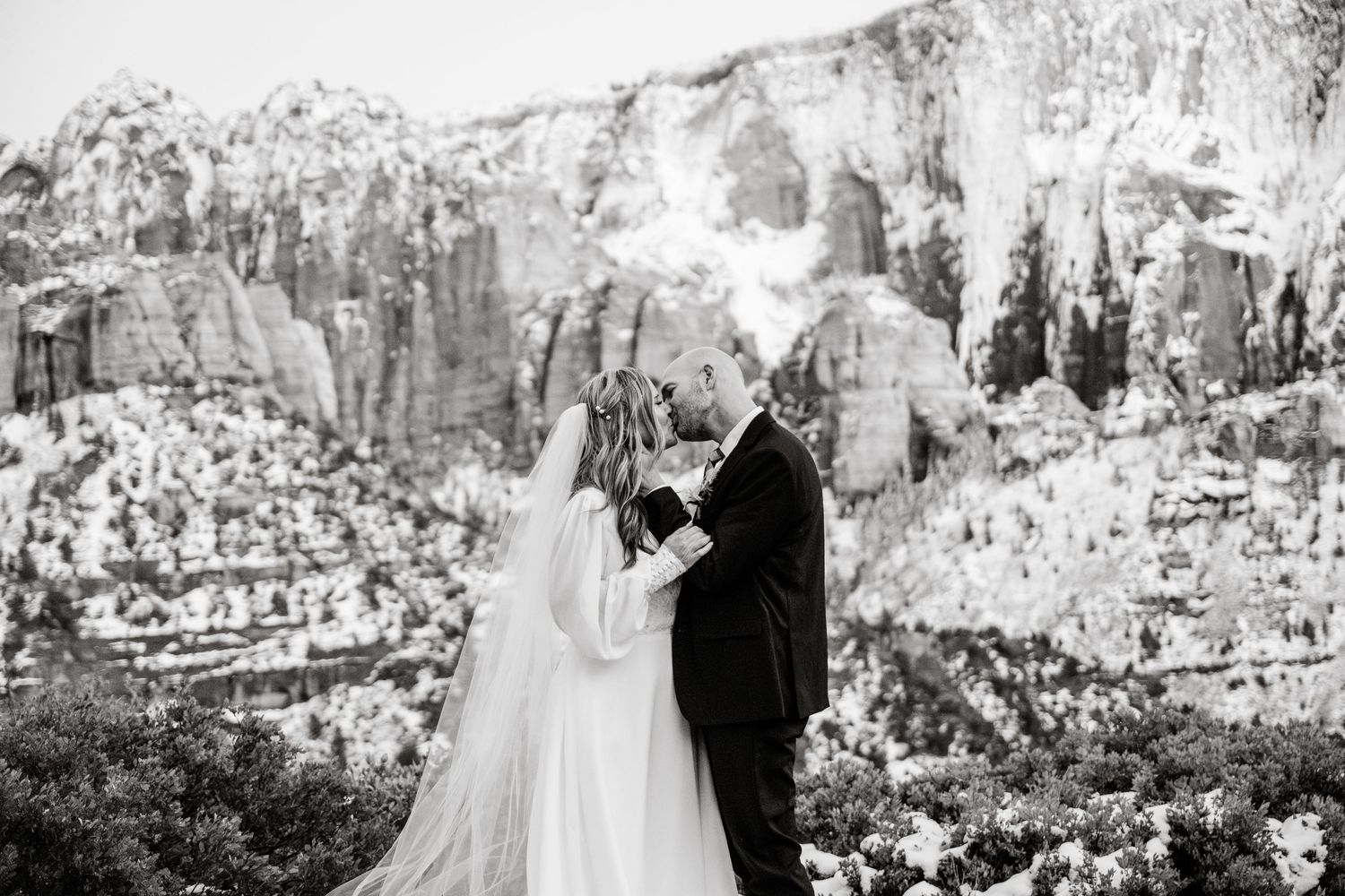 Black and white wedding portraits against dramatic mountain scenery and winter landscape.