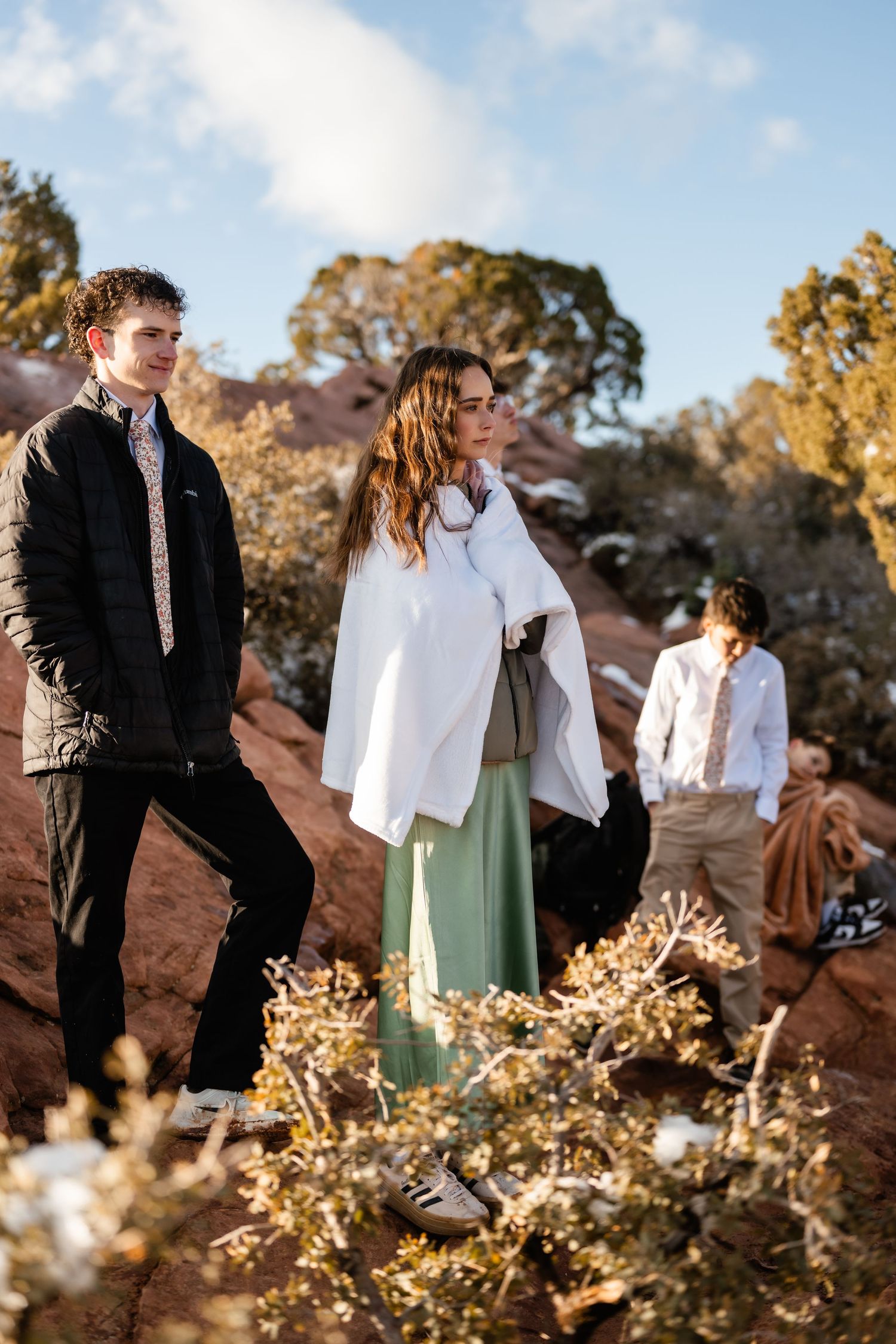 Small group standing on red rock formations during winter day.