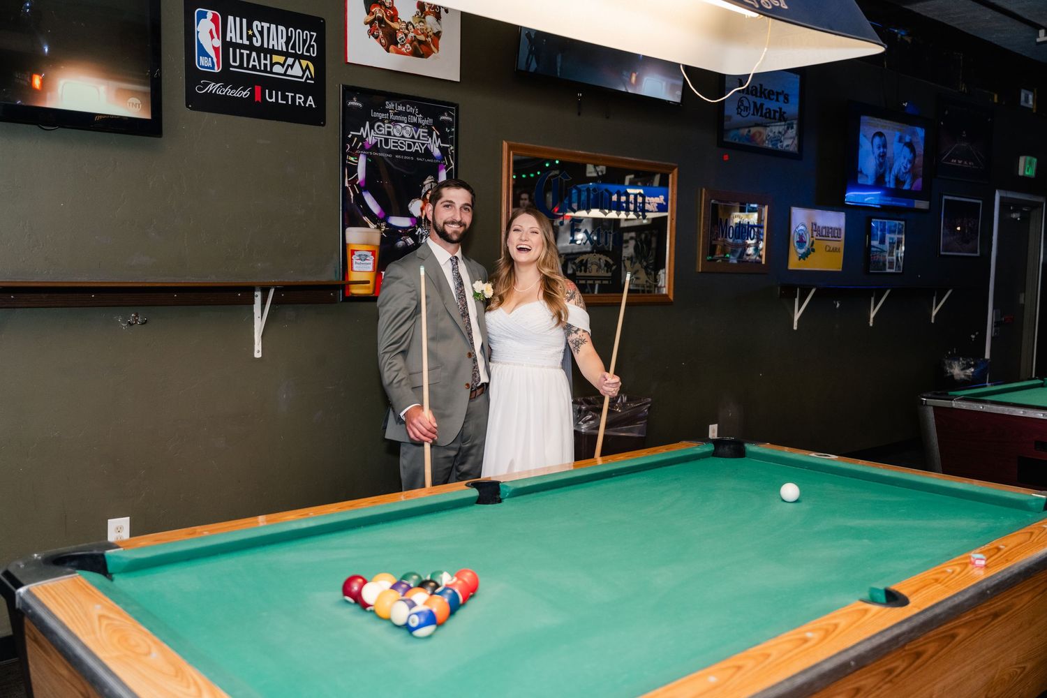 Friends enjoying a game of pool at a bar with pool tables and sports memorabilia on the walls.