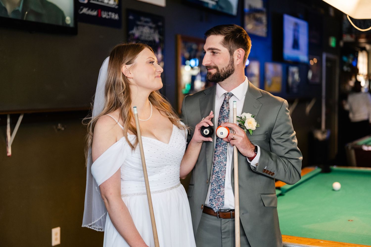 Newlyweds sharing a moment while playing pool at their wedding reception.