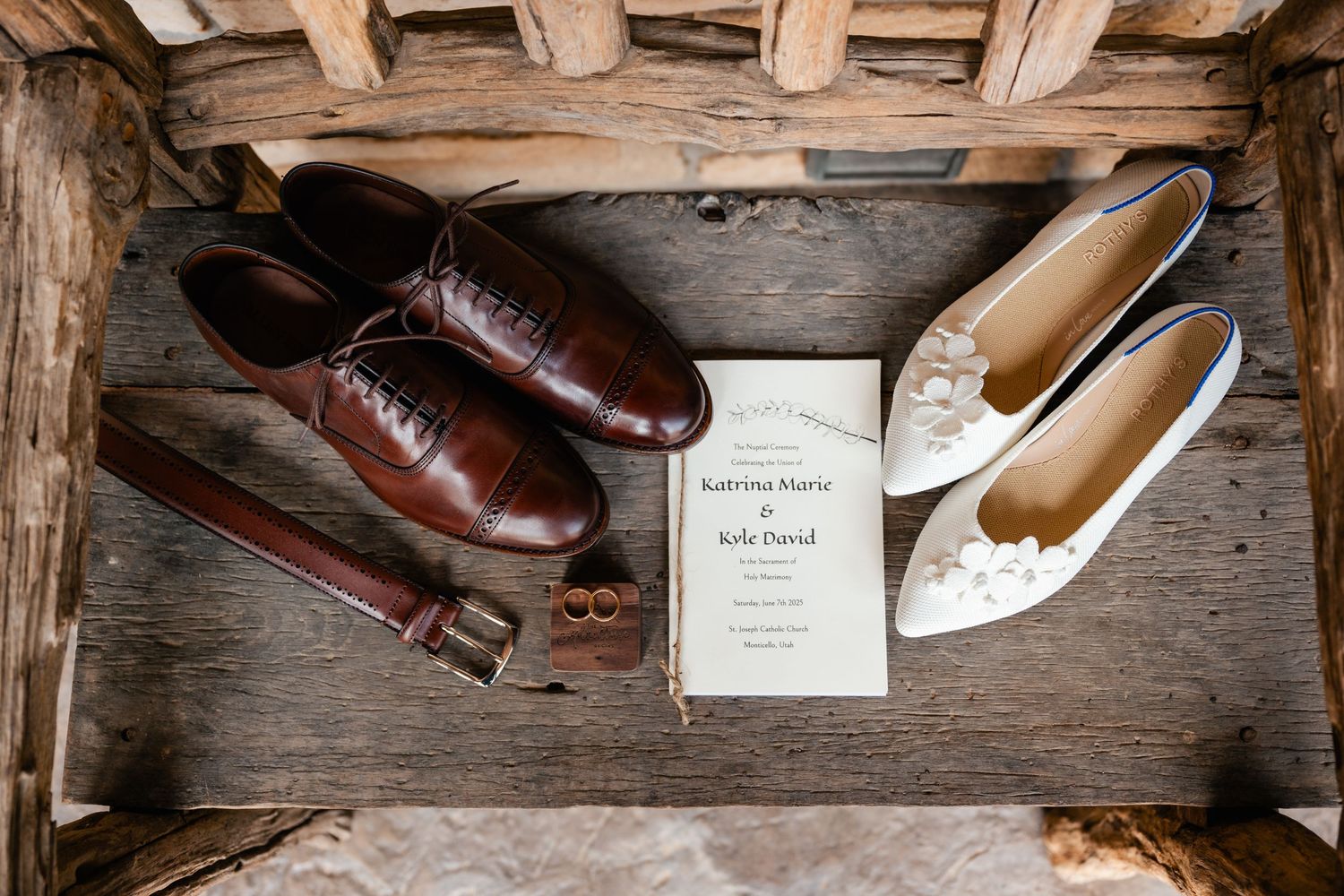 Wedding shoes and invitation displayed in rustic wooden box with brown leather belt.