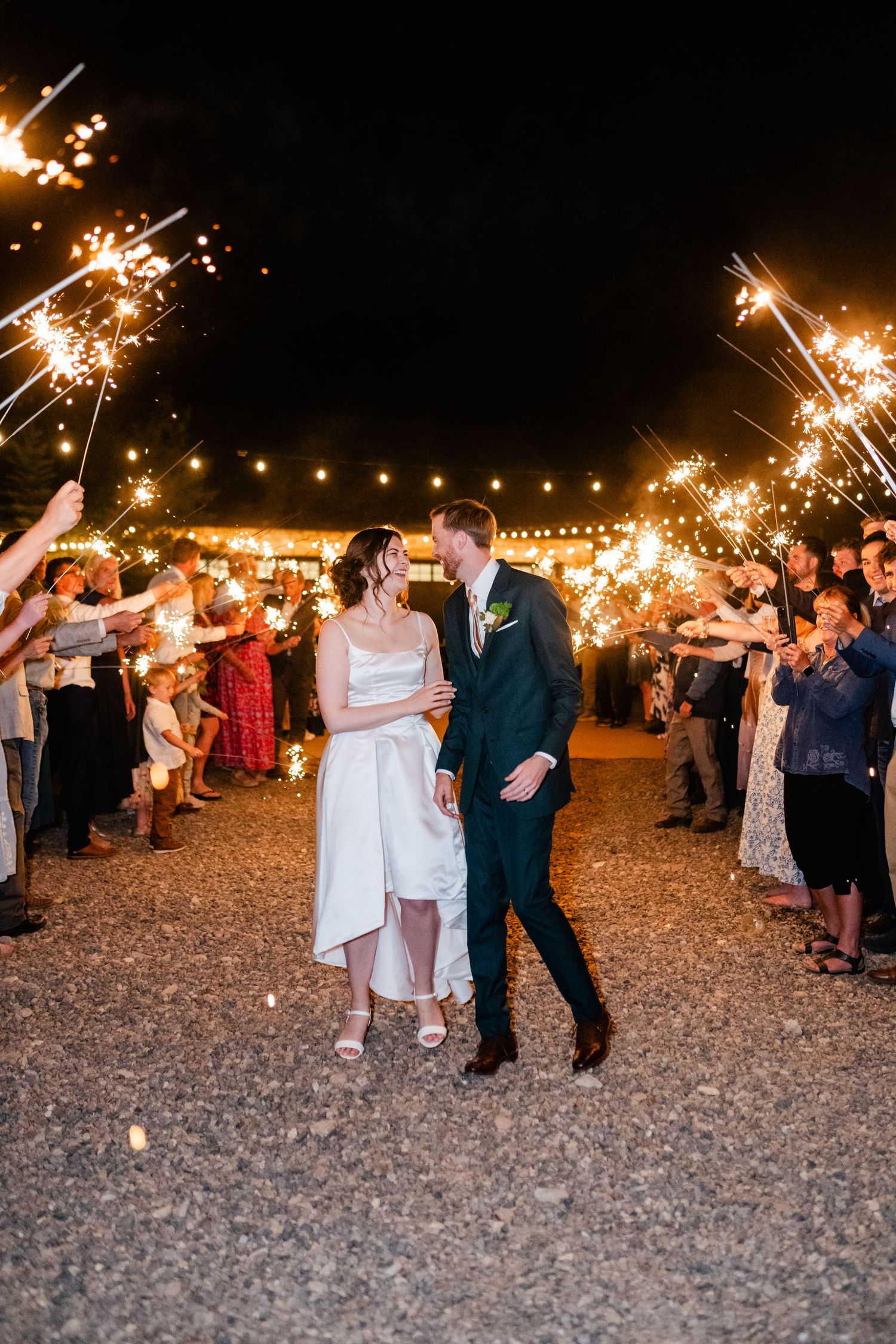 Newlyweds walk through sparkler exit during nighttime wedding celebration.