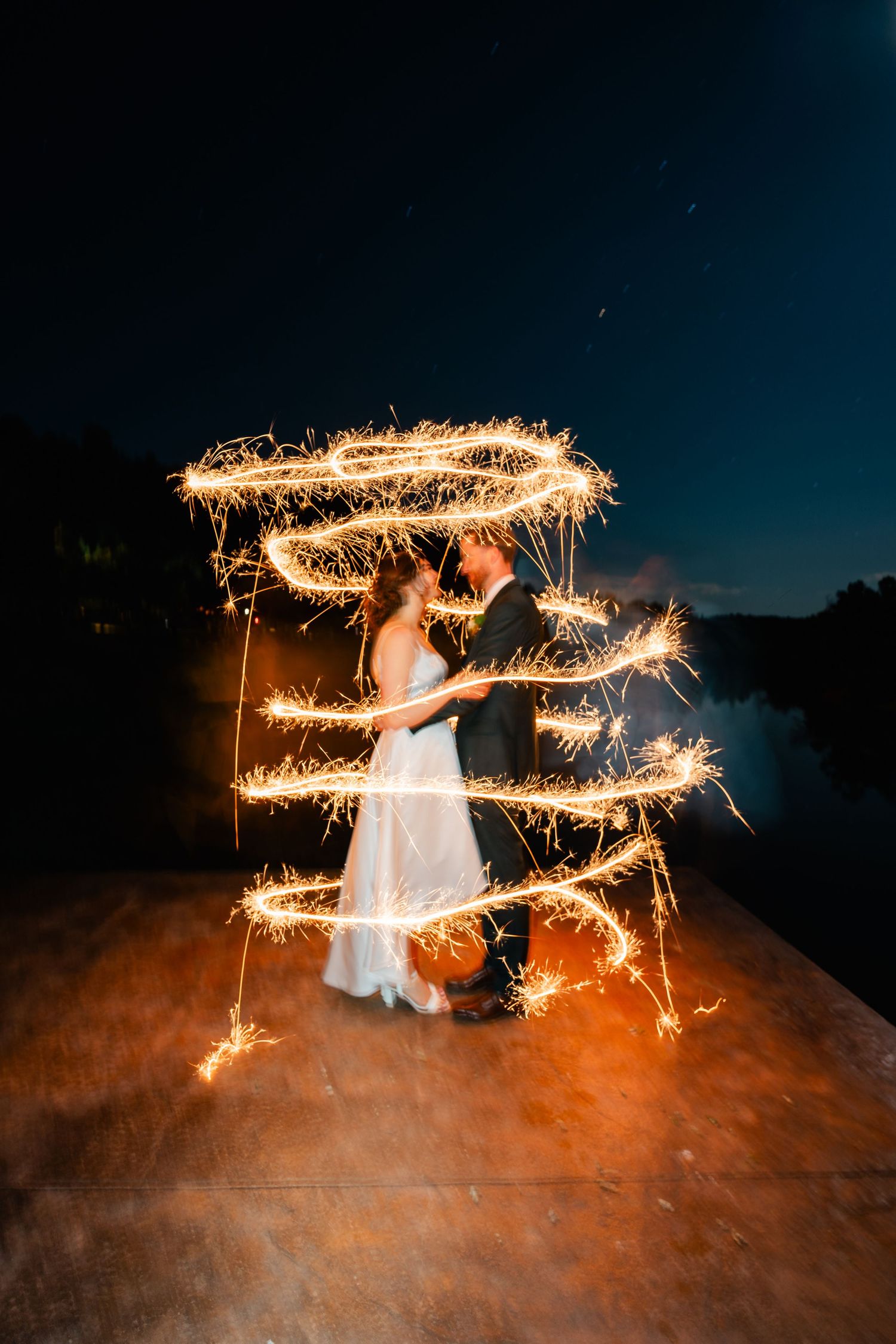 Creative long exposure sparkler photo creates light trails against dark night sky.