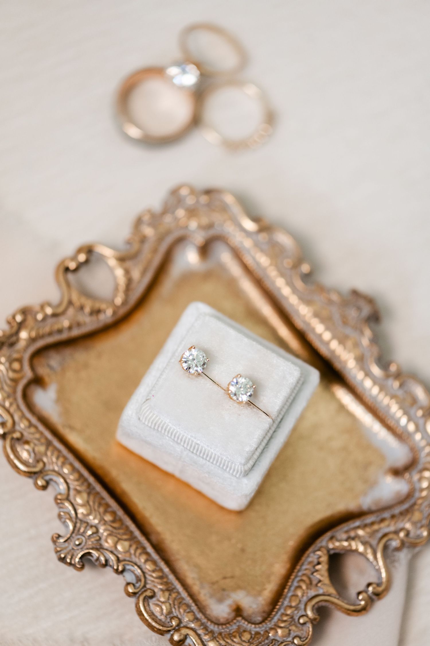 Diamond engagement rings and wedding bands displayed on an ornate gold vintage tray.