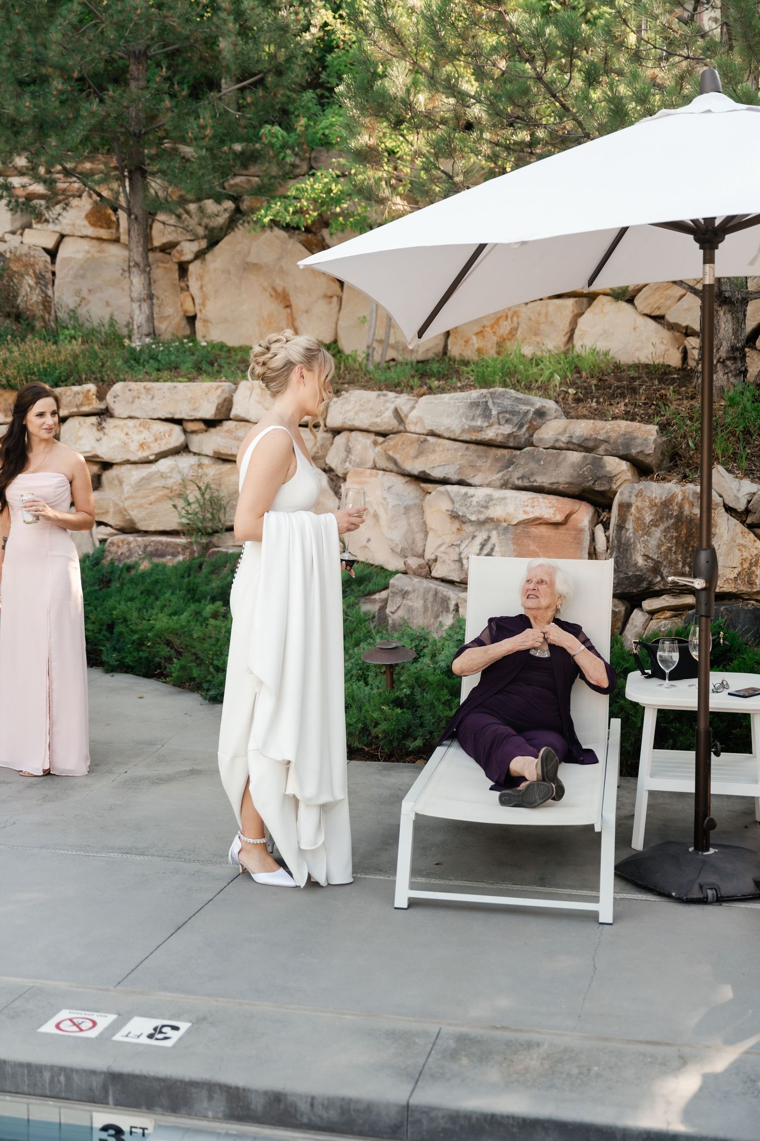 A group enjoys casual moments on an outdoor patio with stone walls and umbrellas.