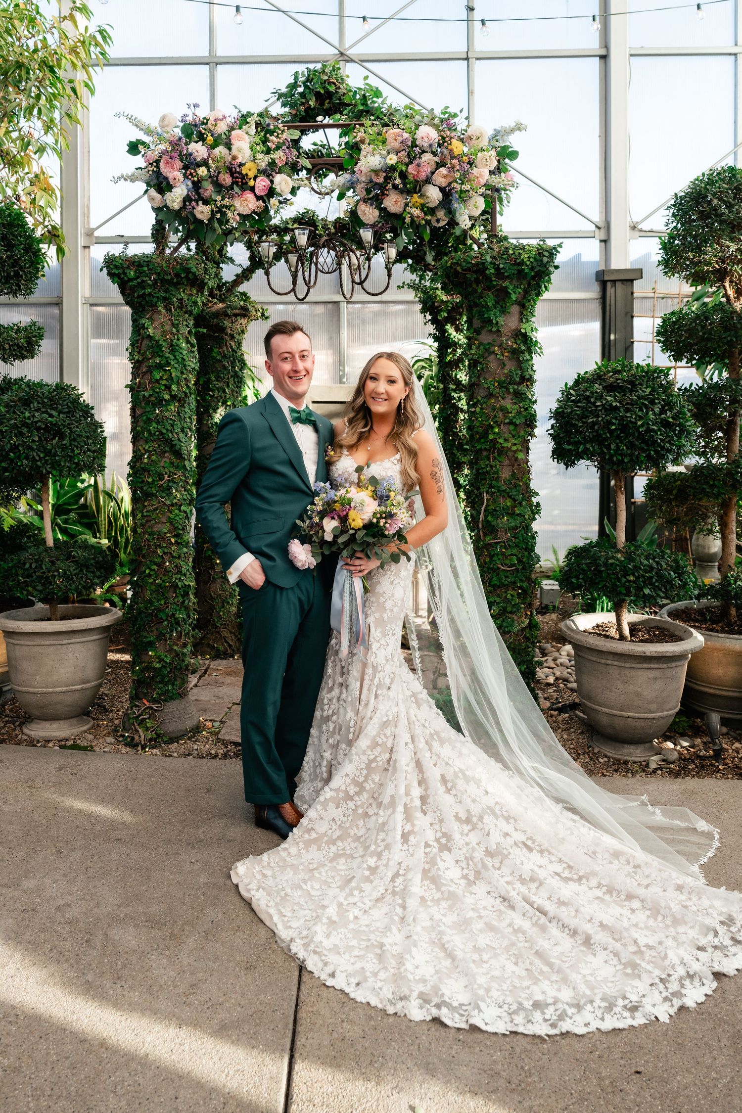 A wedding couple poses in a greenhouse setting at Cactus and Tropicals in Draper, UT. Utah Valley Bride Preferred Vendor Coley Cook.