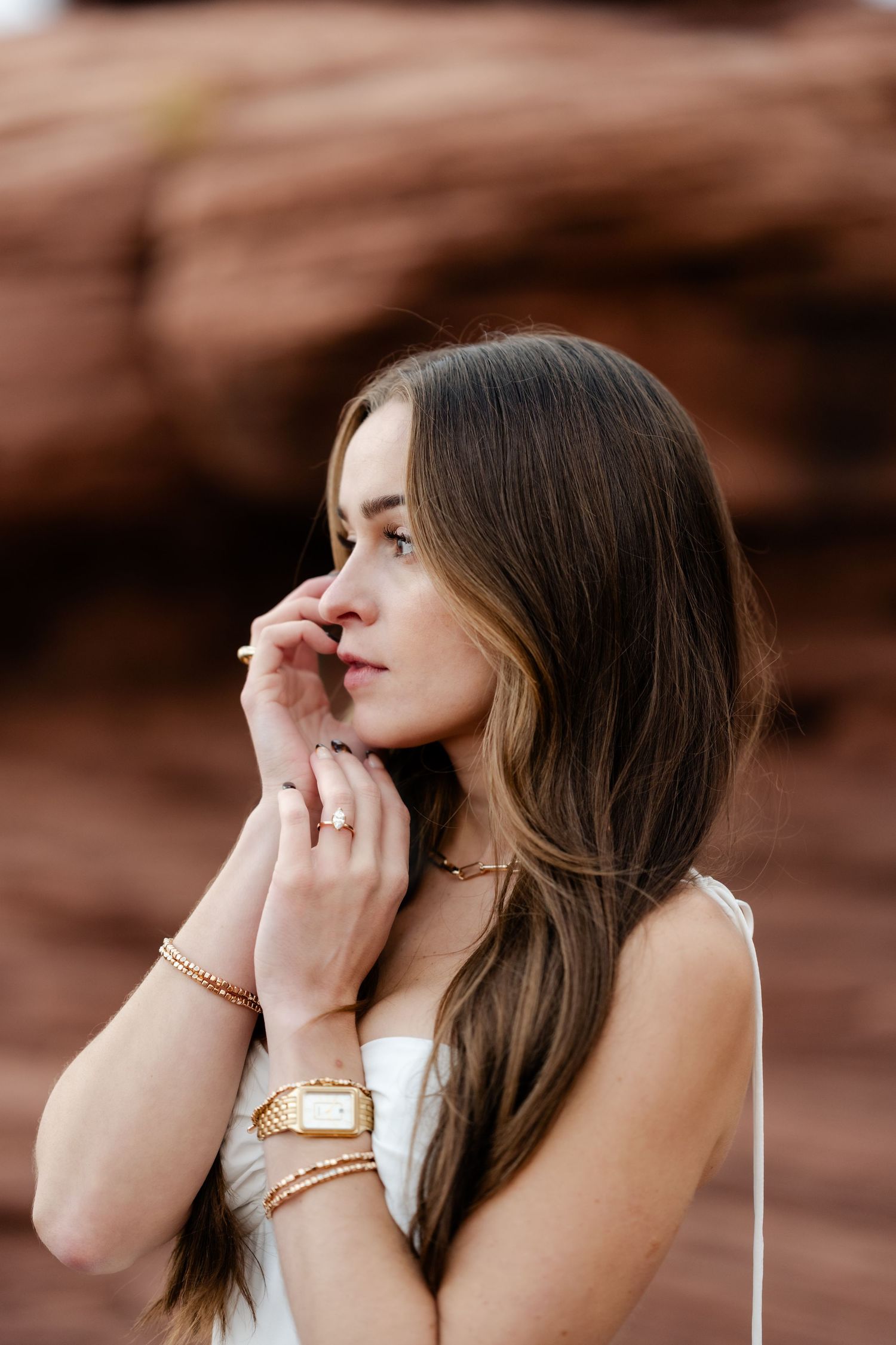 White dress and gold jewelry styled against red rock formations in desert landscape.