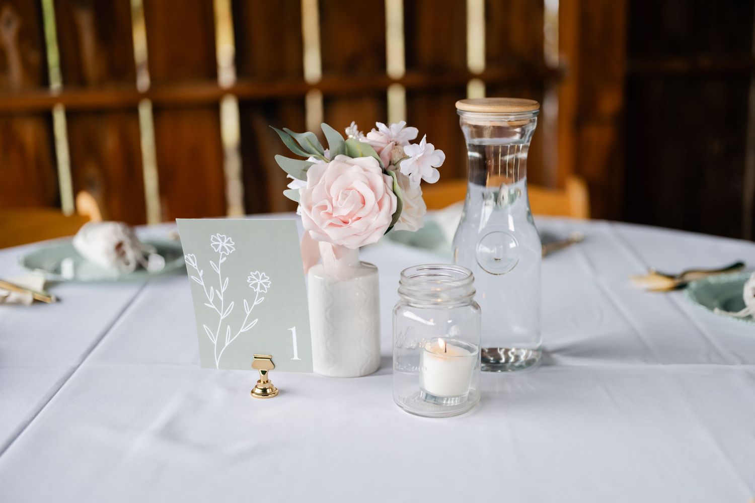 Elegant white tablescape with soft candlelight and delicate floral arrangements for a wedding reception.