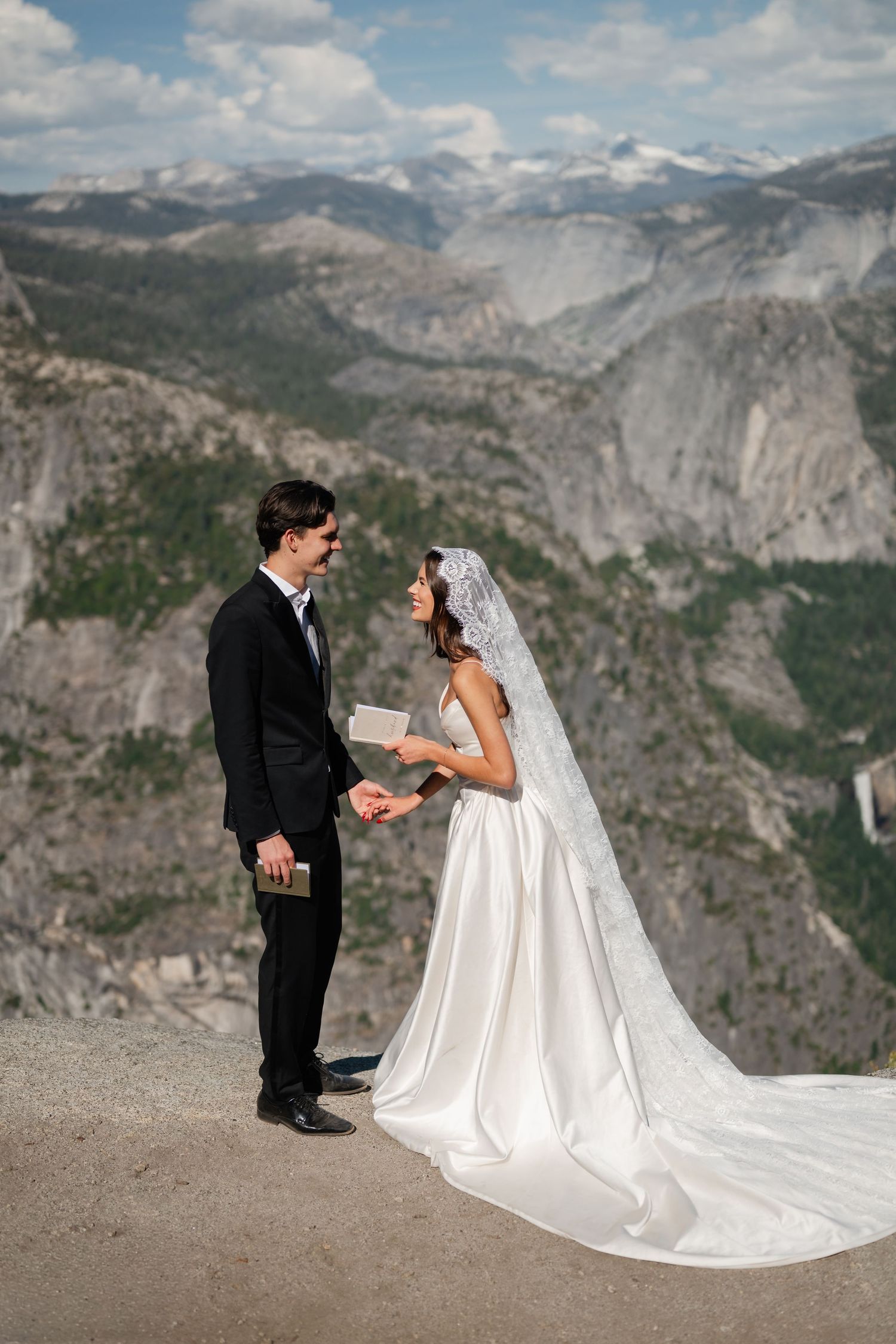 Bride and groom exchange vows on a mountain overlook in Yosemite, with stunning valley views behind them.