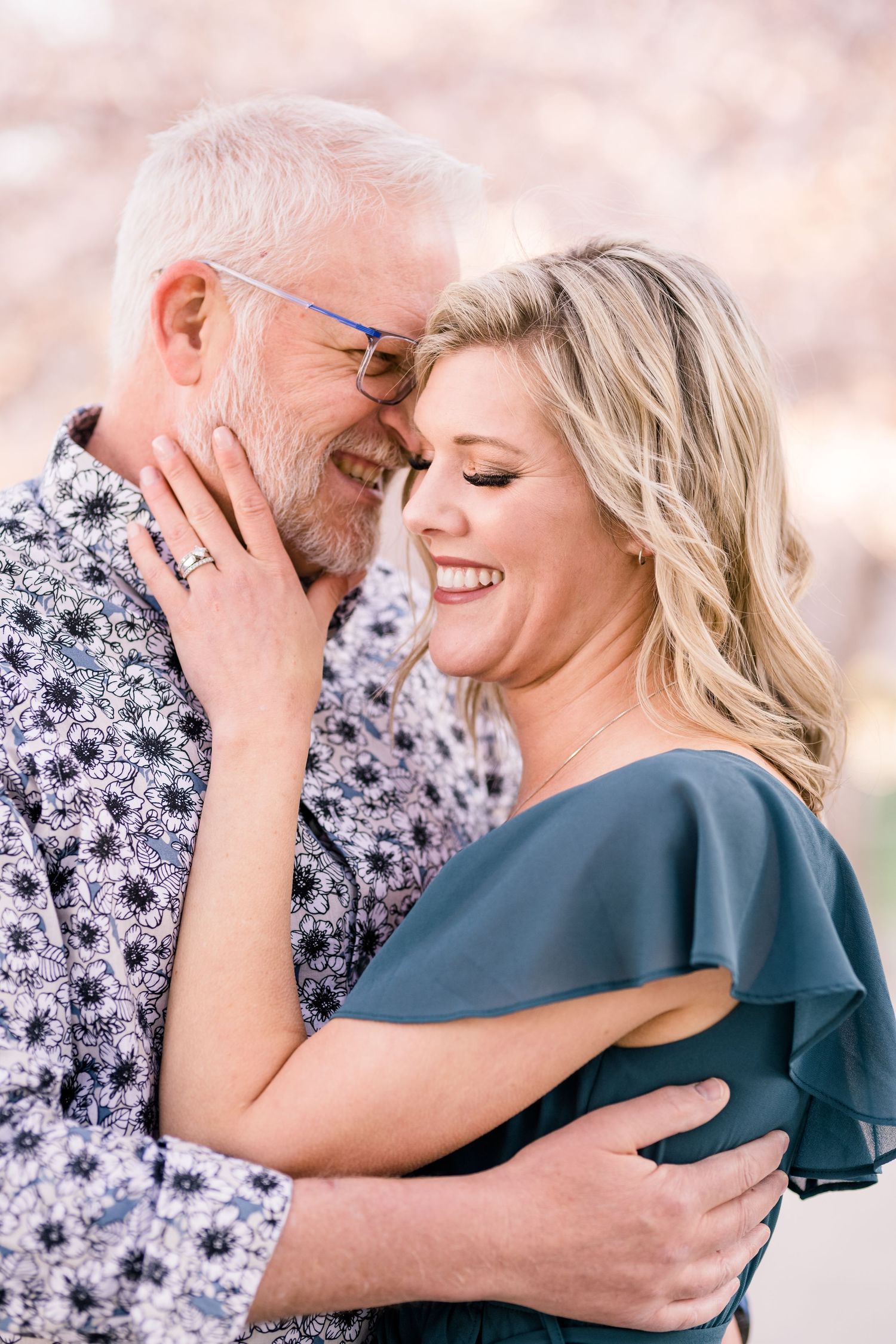 Engaged couple hug warmly at the Capitol cherry blossoms by Utah wedding photographer Coley Cook
