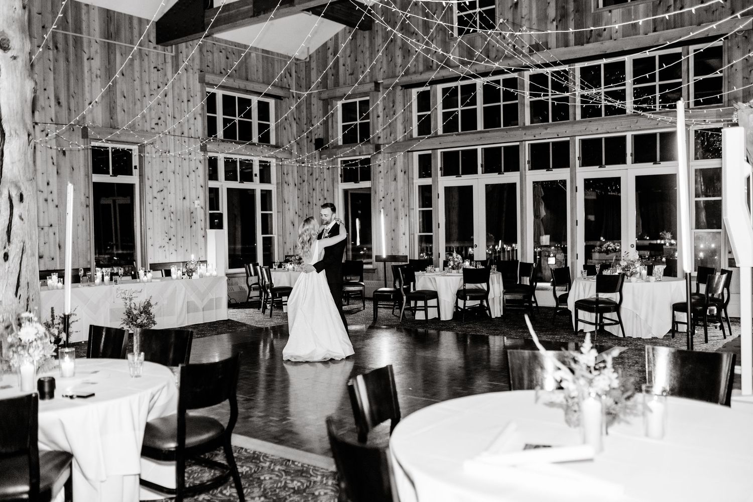 Black and white photo of an elegant wedding reception venue with large windows.
