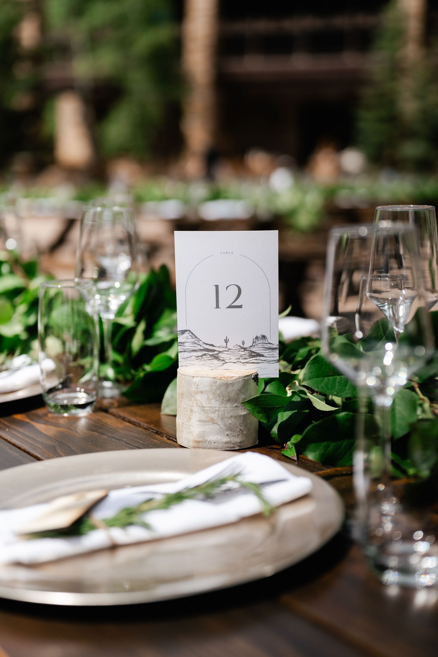 Elegant table settings with greenery and numbered cards at a wedding reception.