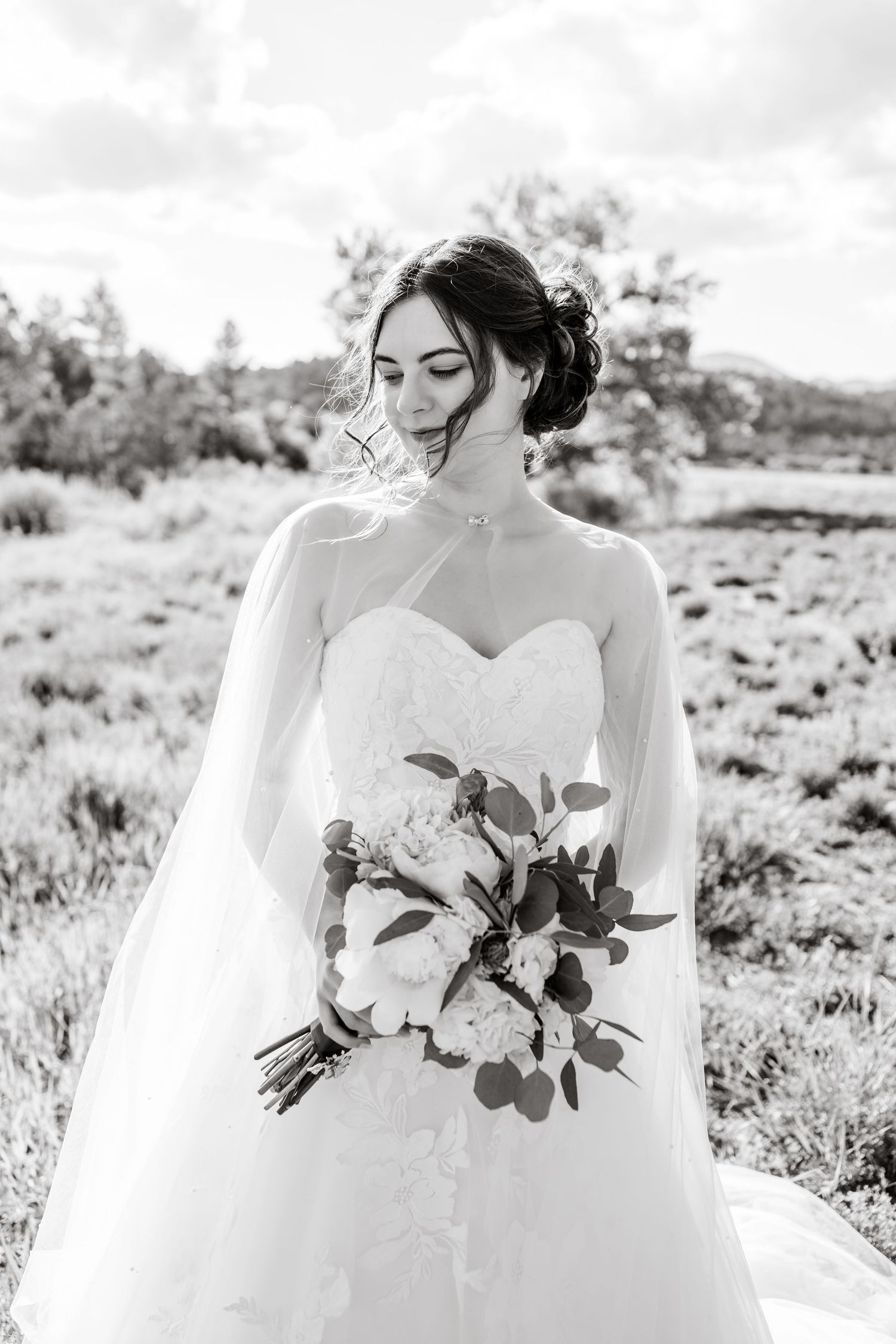 Elegant white wedding dress with floral bouquet captured in black and white photography.