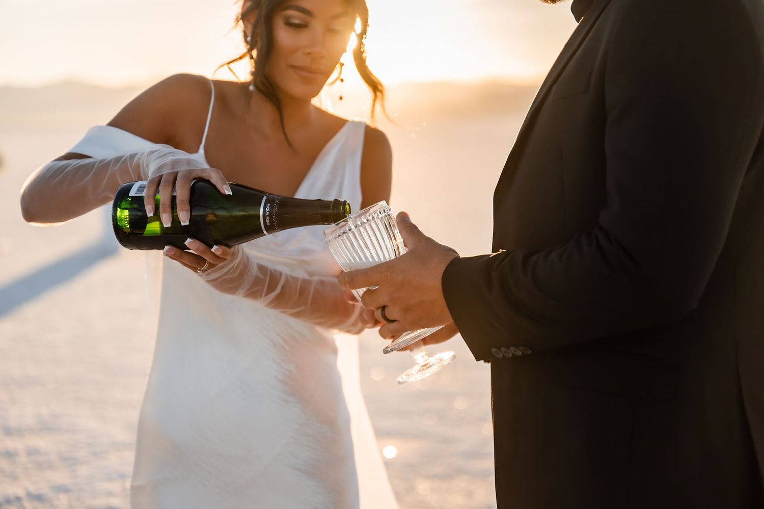 Newlyweds toast with champagne against the ethereal salt flat backdrop.