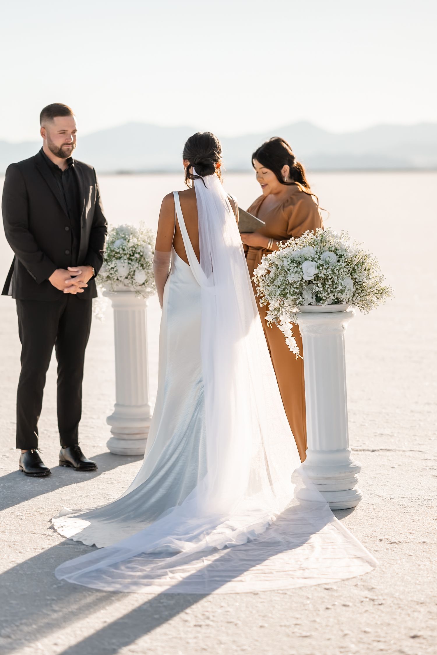 Wedding ceremony on salt flats with white floral arrangements on pedestals.