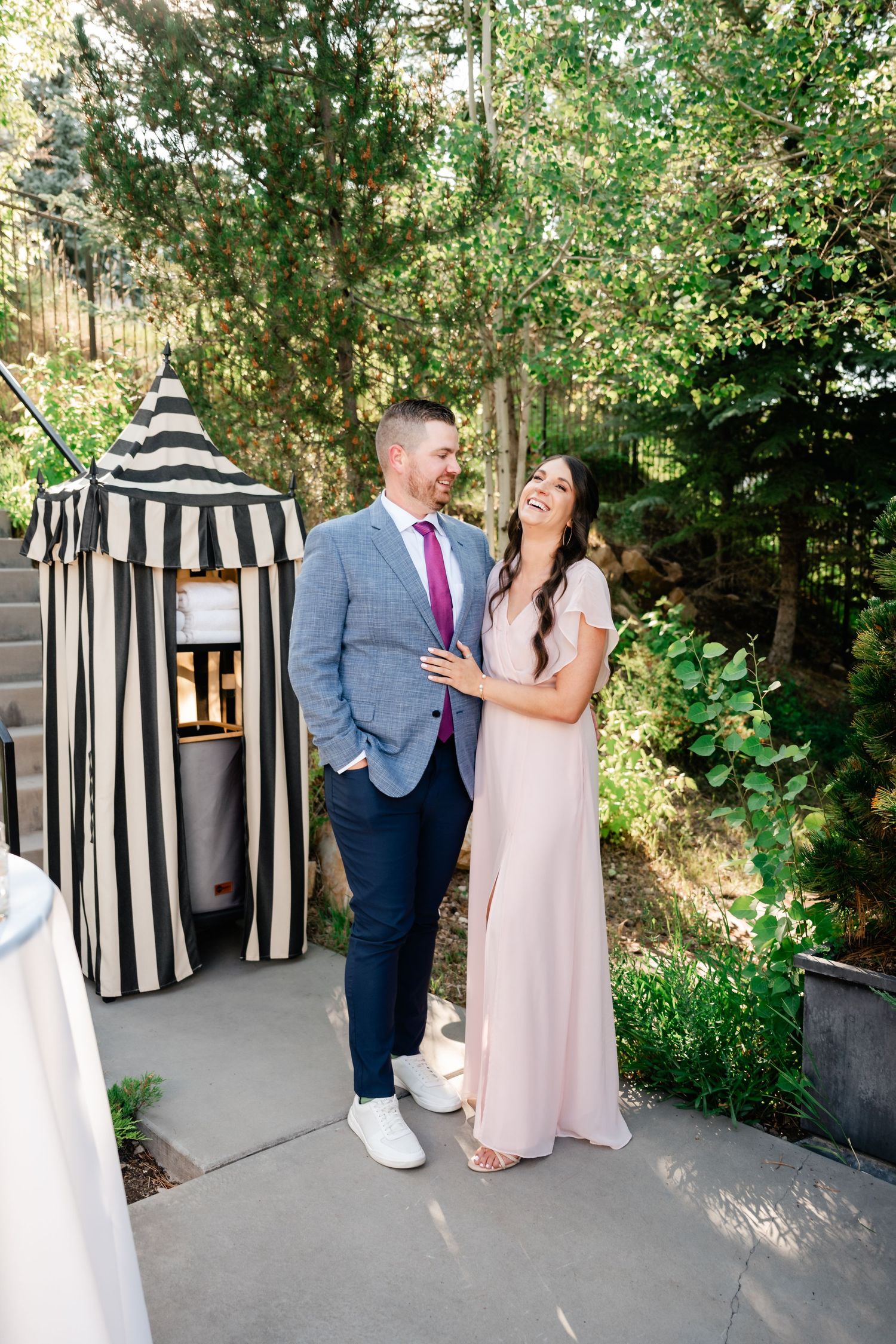 A couple shares a romantic moment in a garden setting with black and white striped decor.