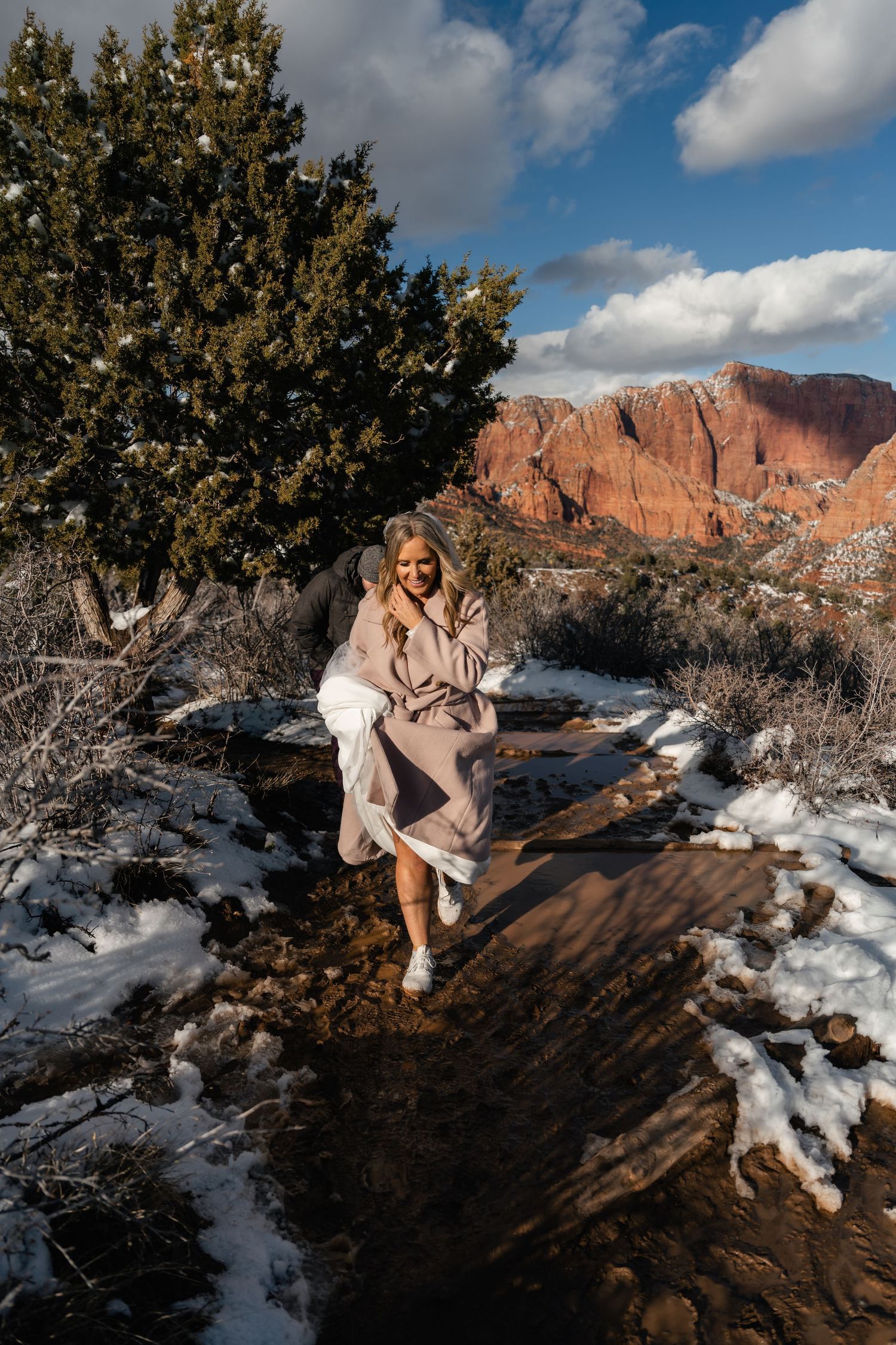 Wedding portraits in a snowy desert landscape with juniper trees and red rock formations.
