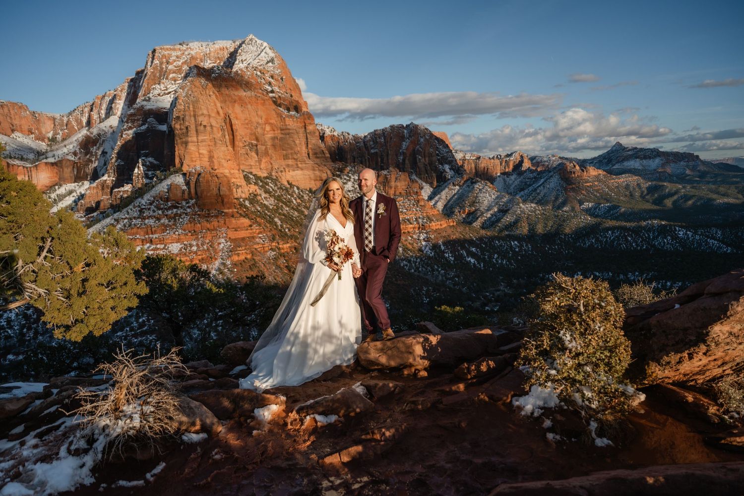 Panoramic view of red rock cliffs and snow-covered mountains during winter wedding ceremony.