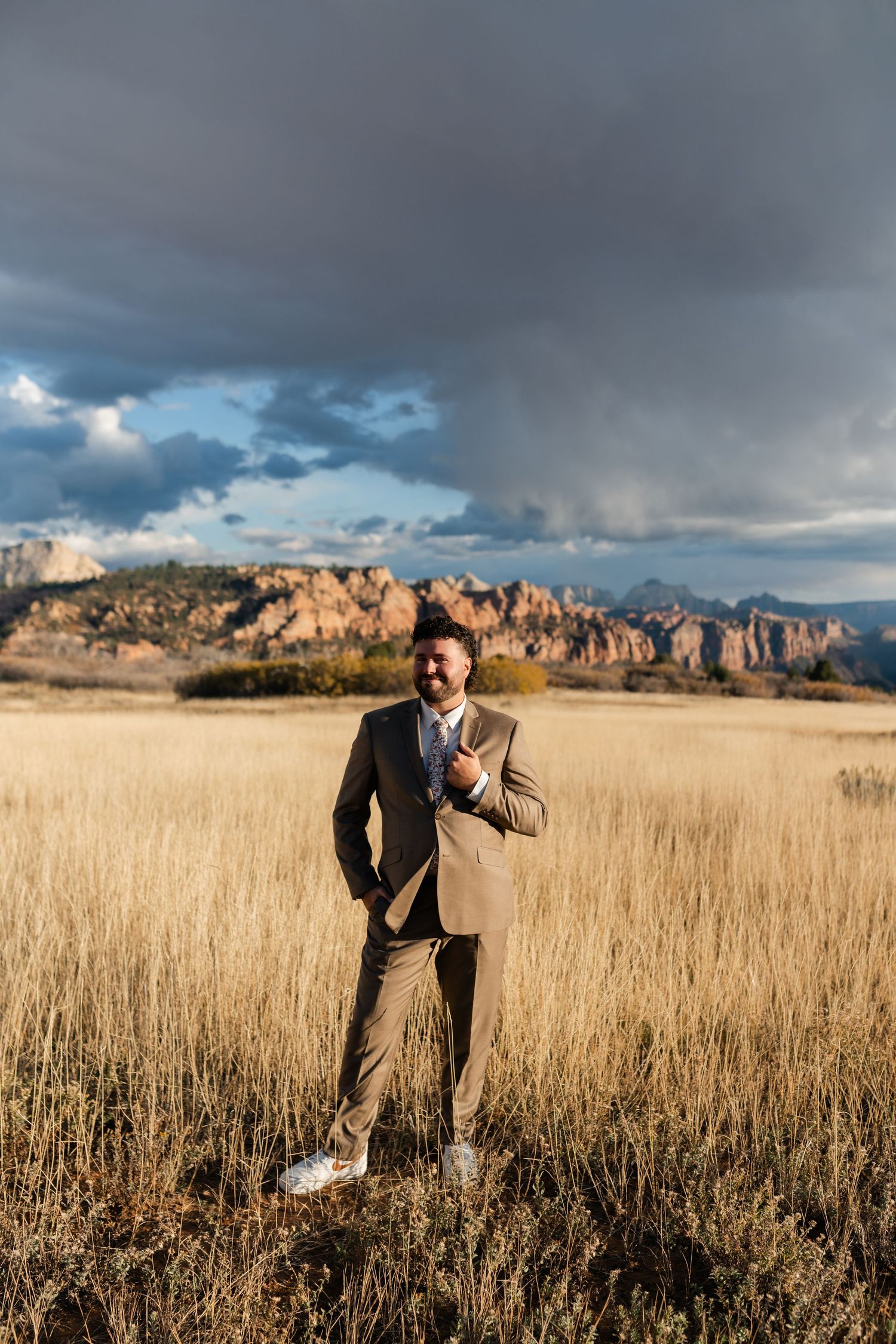 Dramatic wedding photography in golden prairie grass with mountain landscape.