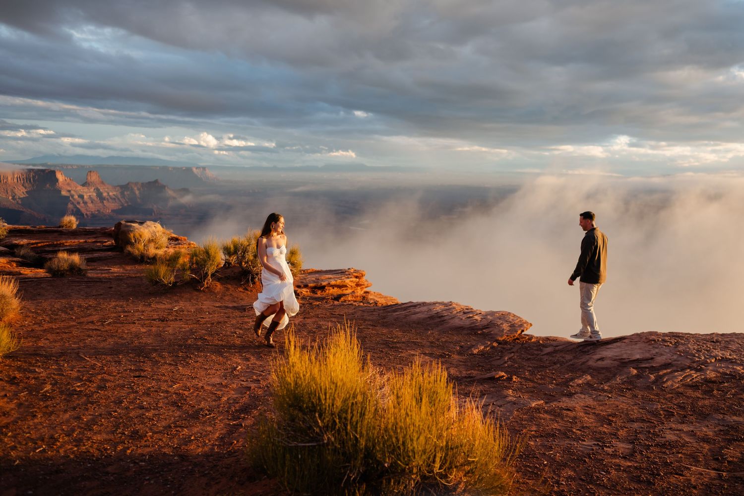 Dramatic desert landscape with red rock formations under stormy skies at sunset.