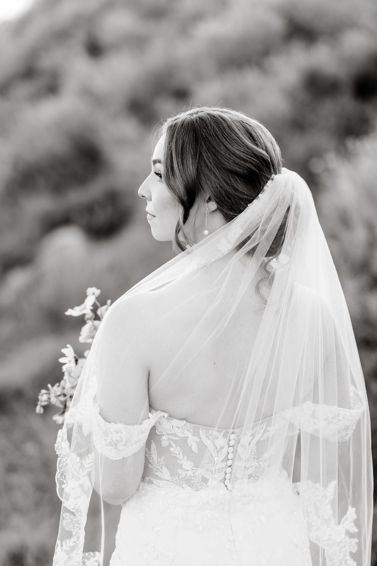 Delicate lace details of a white wedding dress and veil captured in black and white.