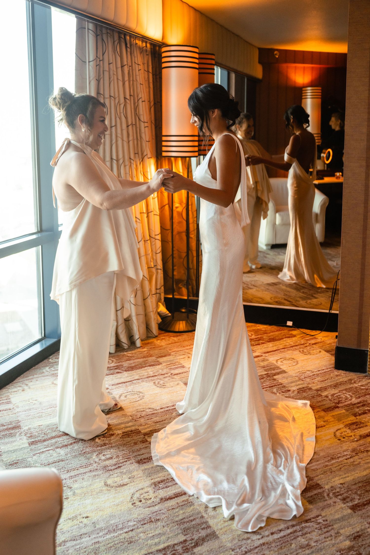 Getting ready sequence showing a bride in a flowing white dress preparing in an elegantly lit hotel room.