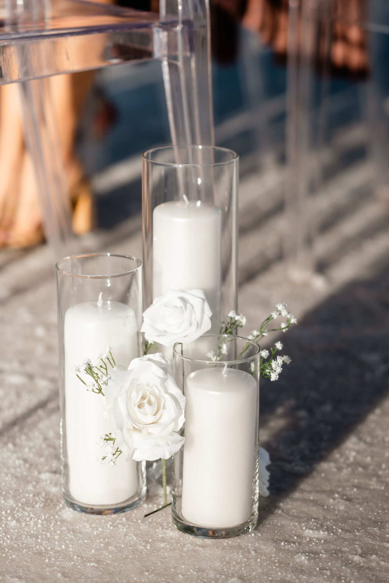 White candles in glass holders decorated with delicate white flowers create an elegant wedding ambiance.