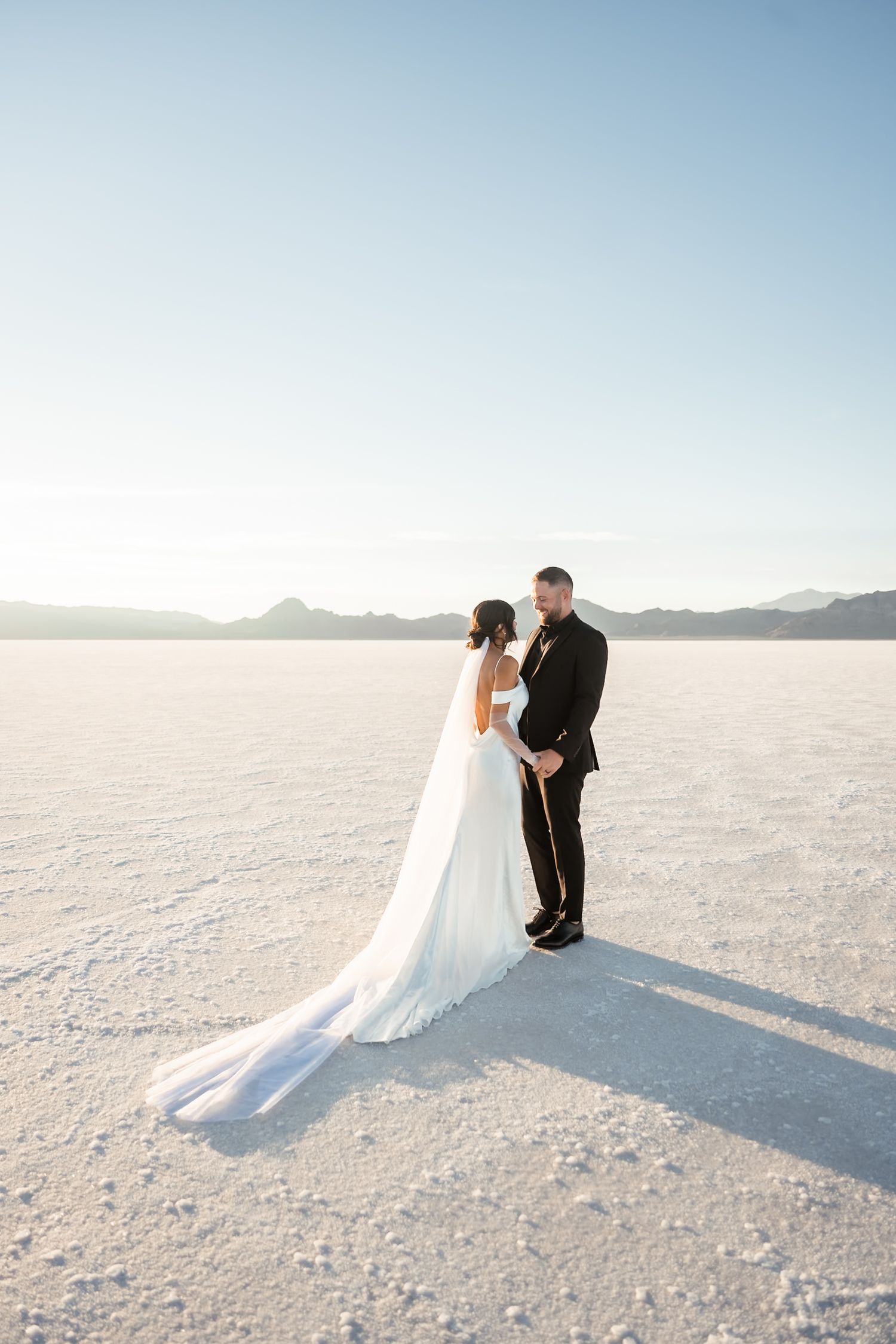 Wedding couple shares romantic moments on vast white salt flats landscape.