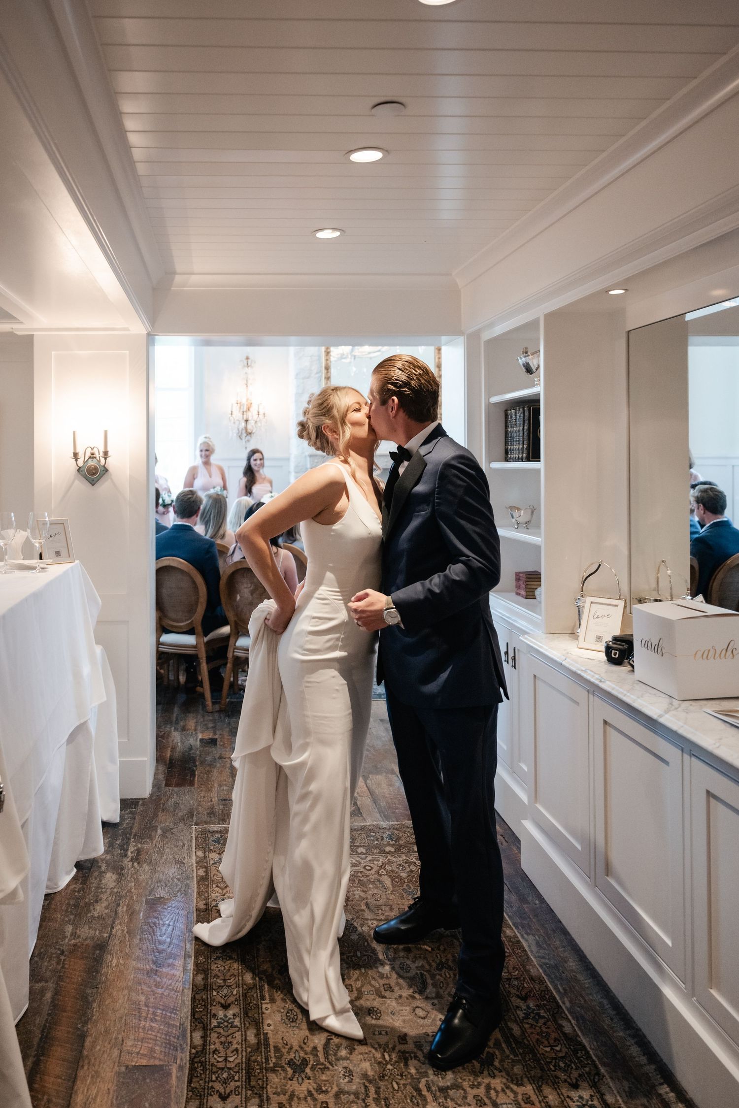 Wedding celebration sequence in a bright hallway with white wainscoting and hardwood floors.