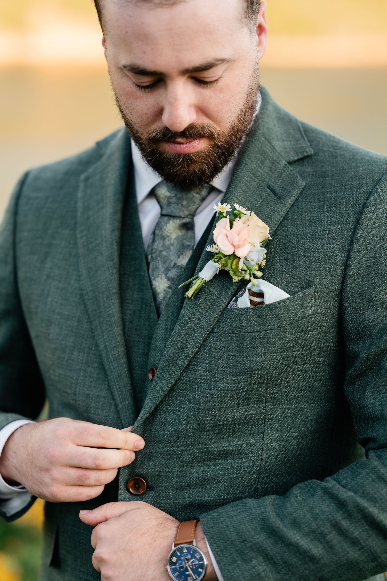 Detail shots of groom's boutonniere and dark green suit jacket.