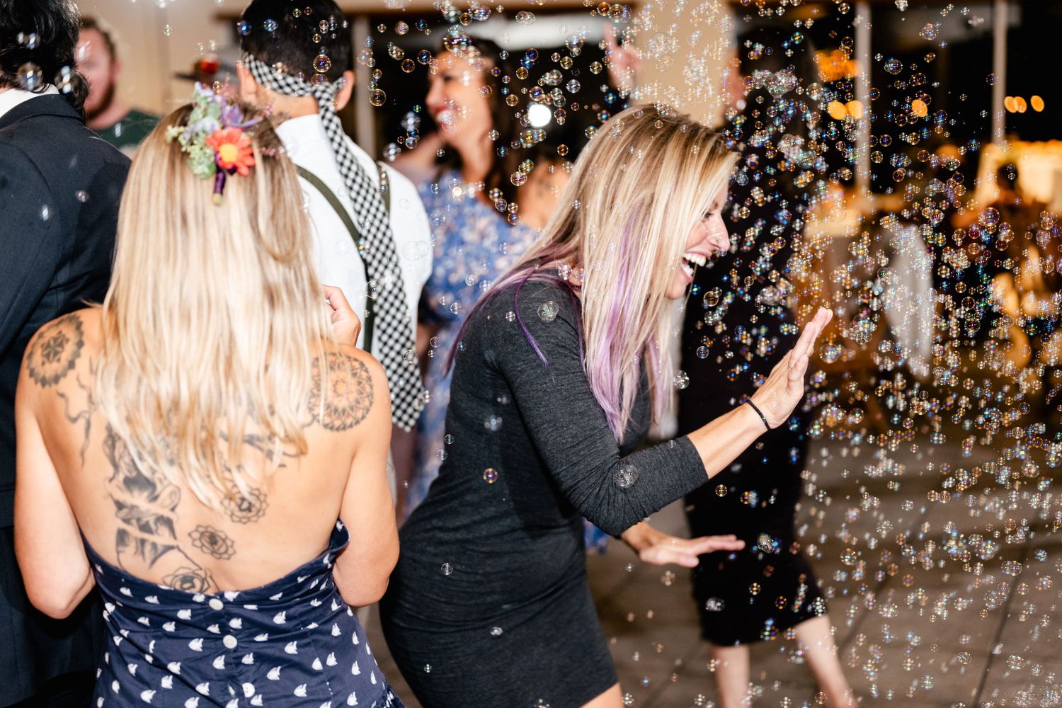 Party guests dance under falling confetti during a nighttime celebration.