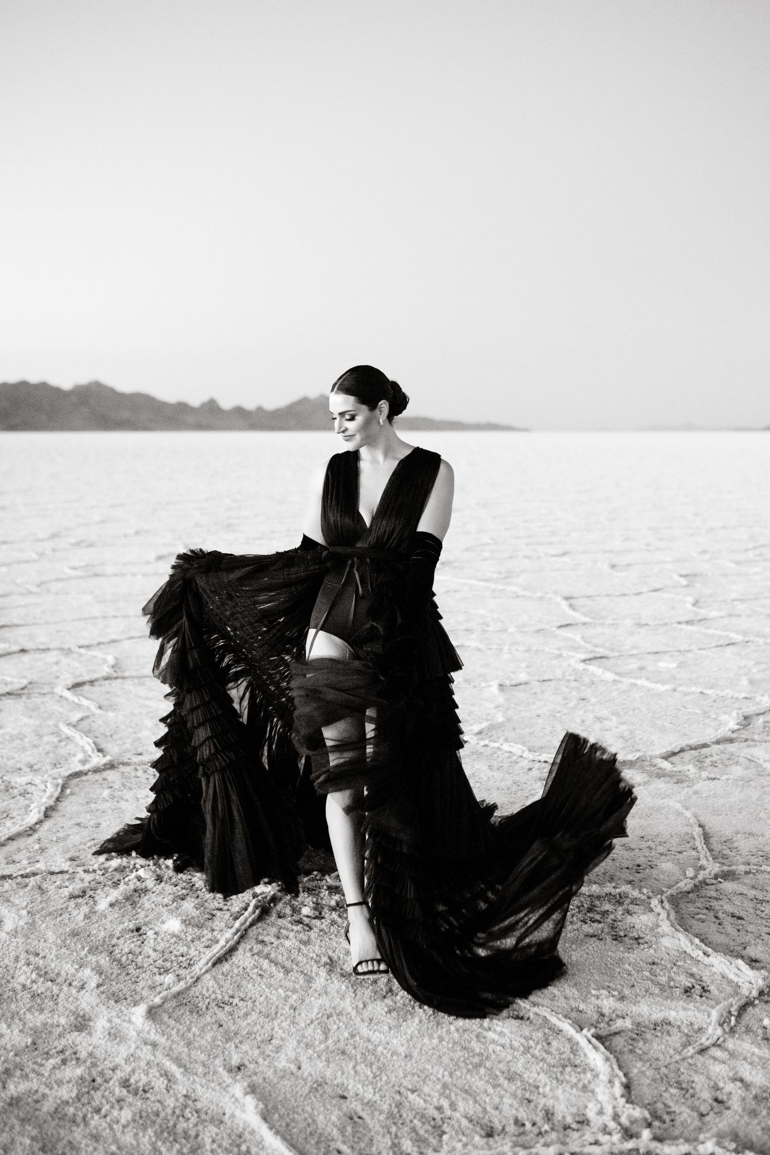 Utah Salt Flats Photographer. Black and white photo of dramatic black dress with ruffles on salt flats landscape.