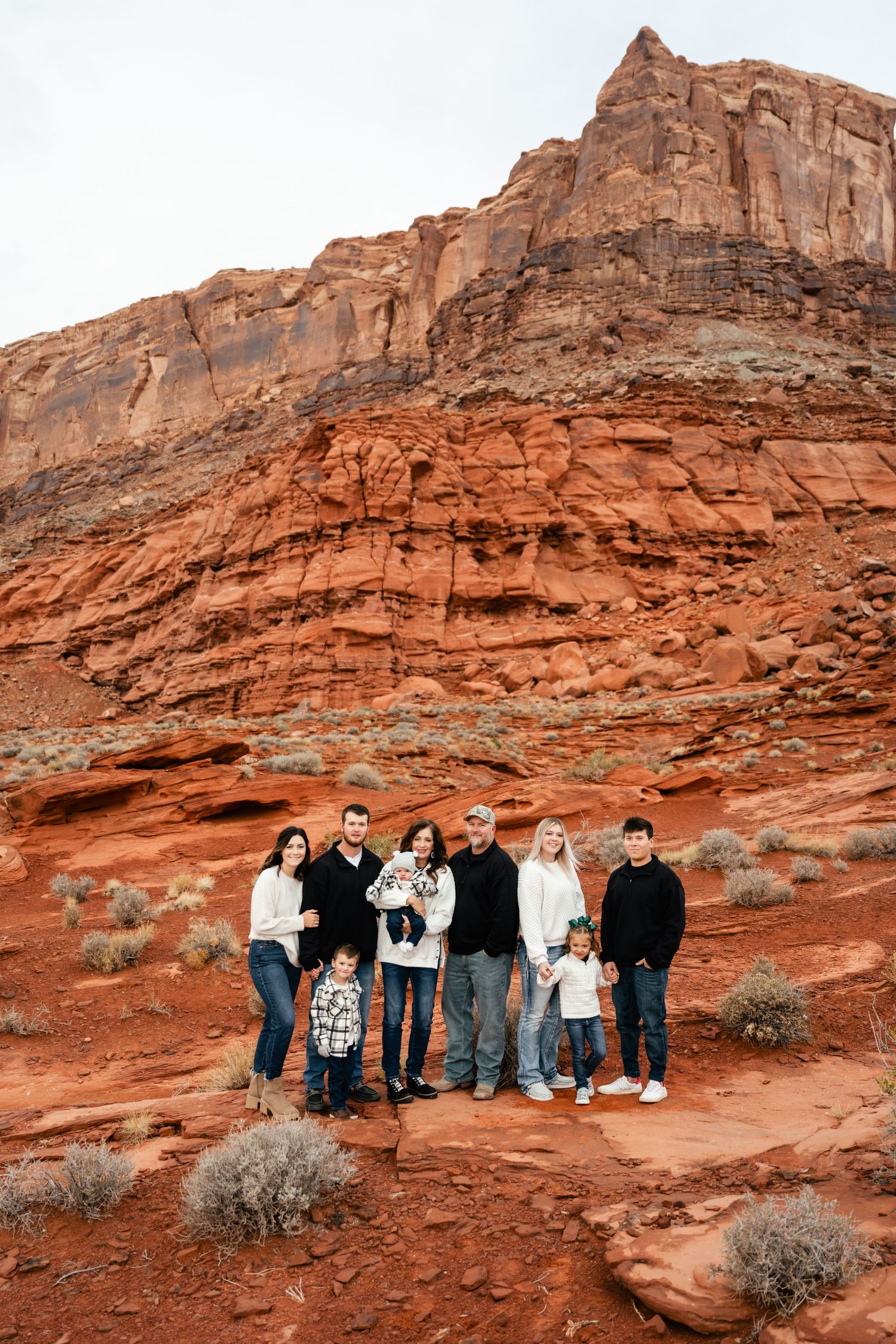 People lined up against dramatic red rock formations in what appears to be a desert national park setting.