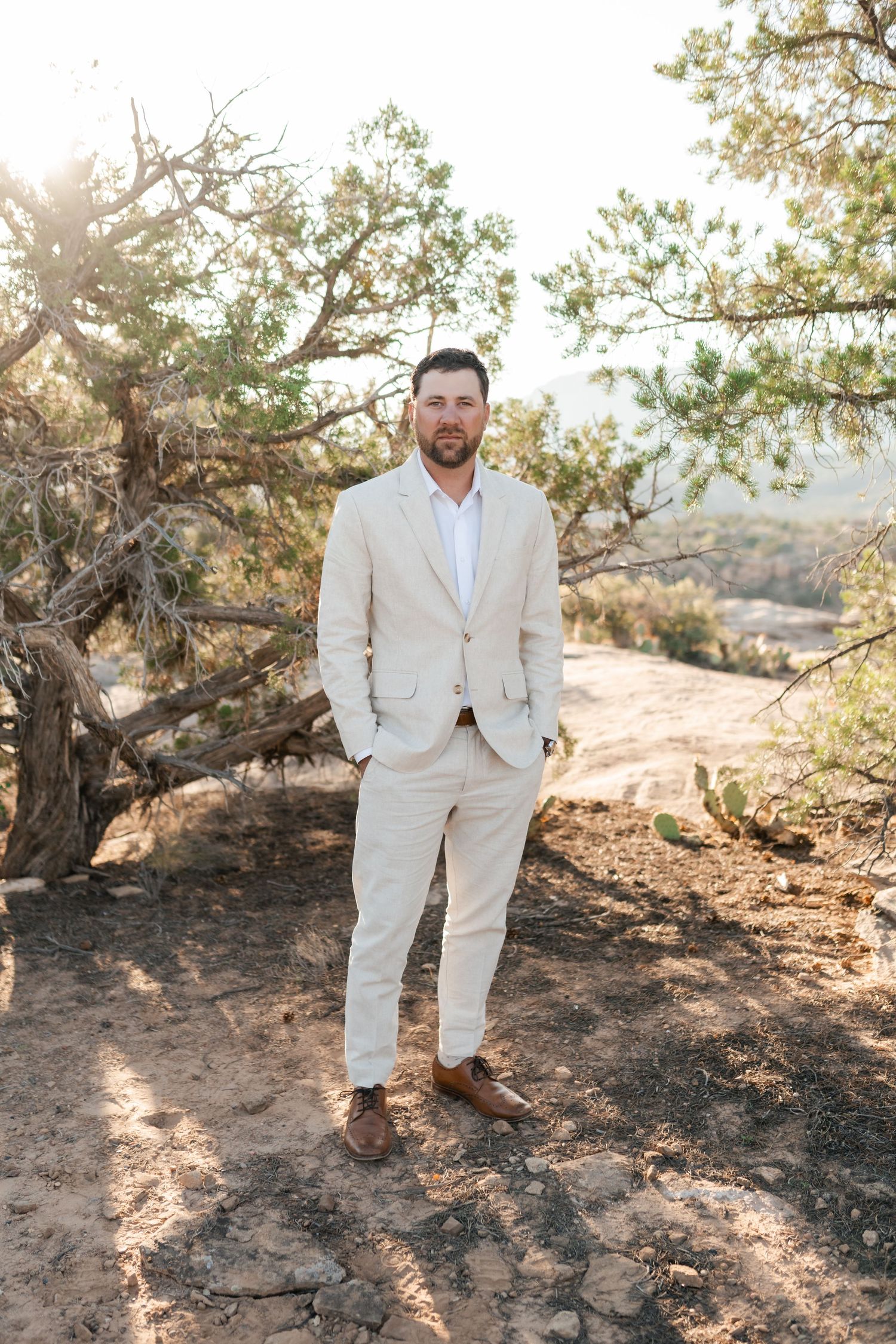 Zion destination photographer, A person in a light colored suit poses on rocky desert terrain during golden hour.