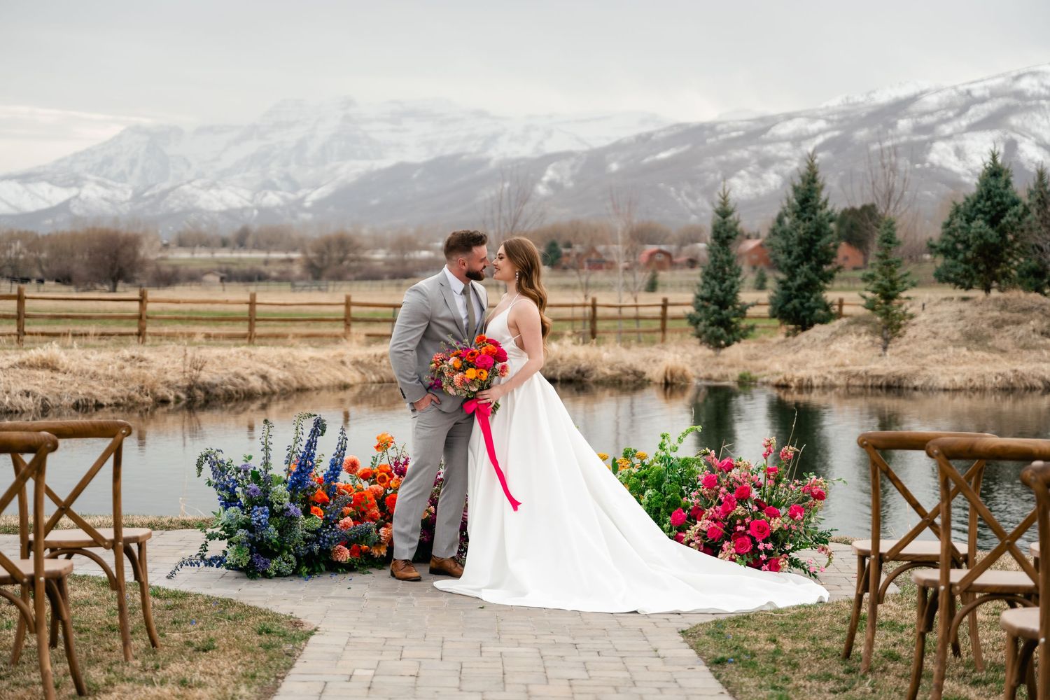 A romantic winter wedding scene in a snowy mountain landscape with rustic wooden decor and red floral accents.