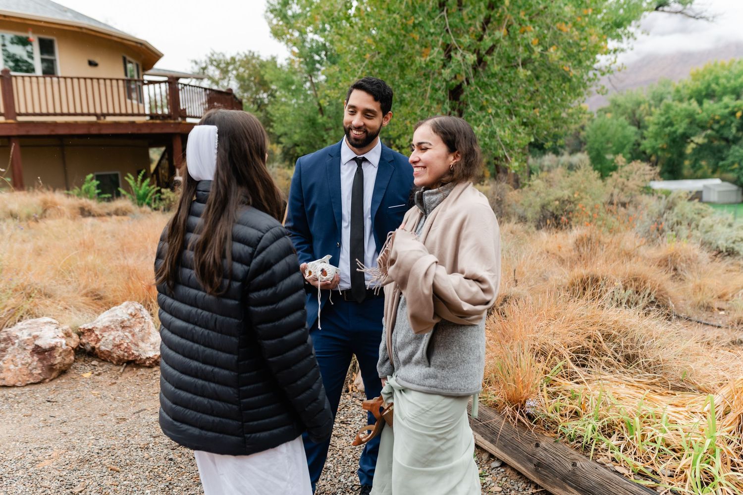Guests mingling on a rustic wooden deck with mountain views in the background.