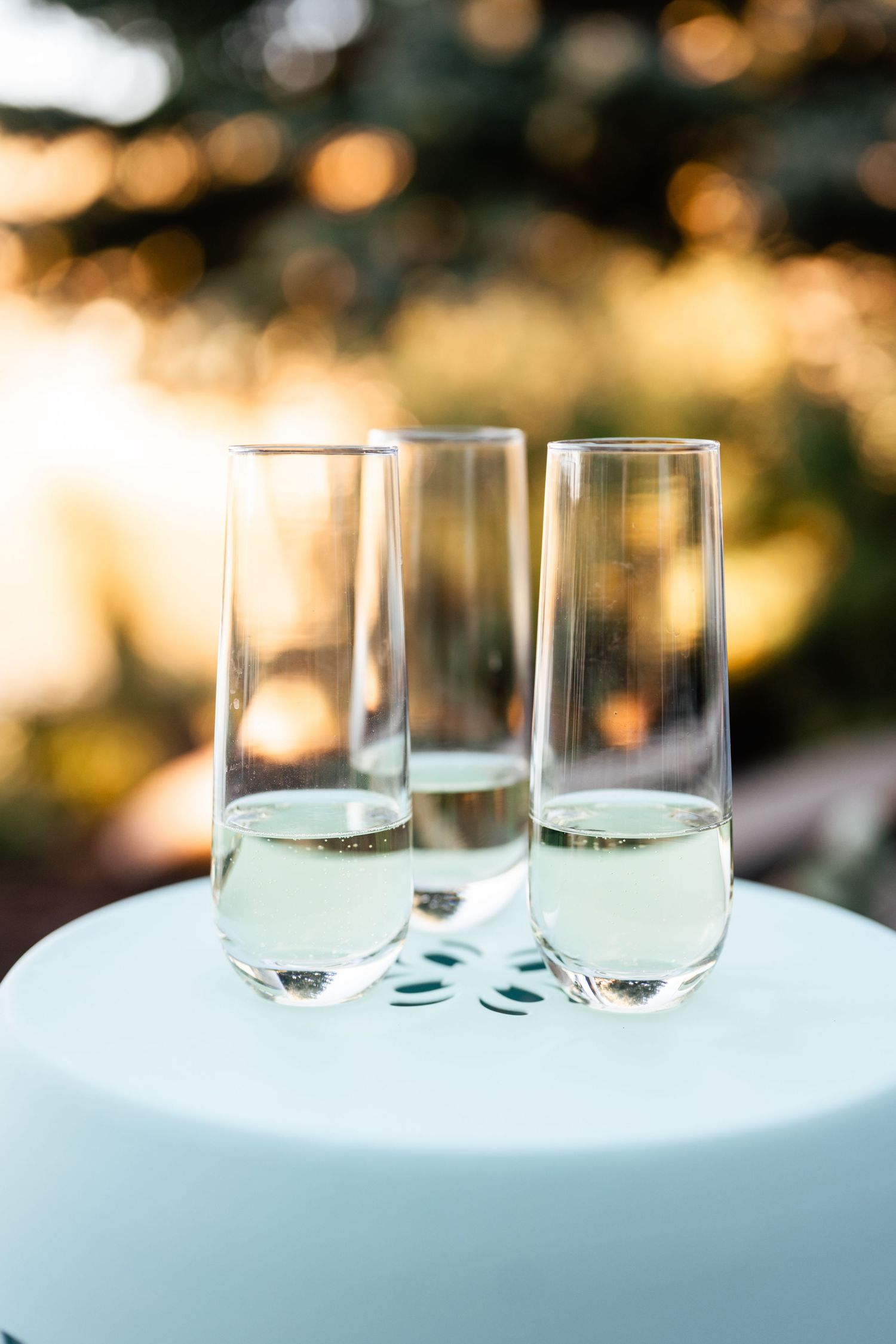 Elegant champagne glasses arranged on a white surface with soft bokeh lights in the background.