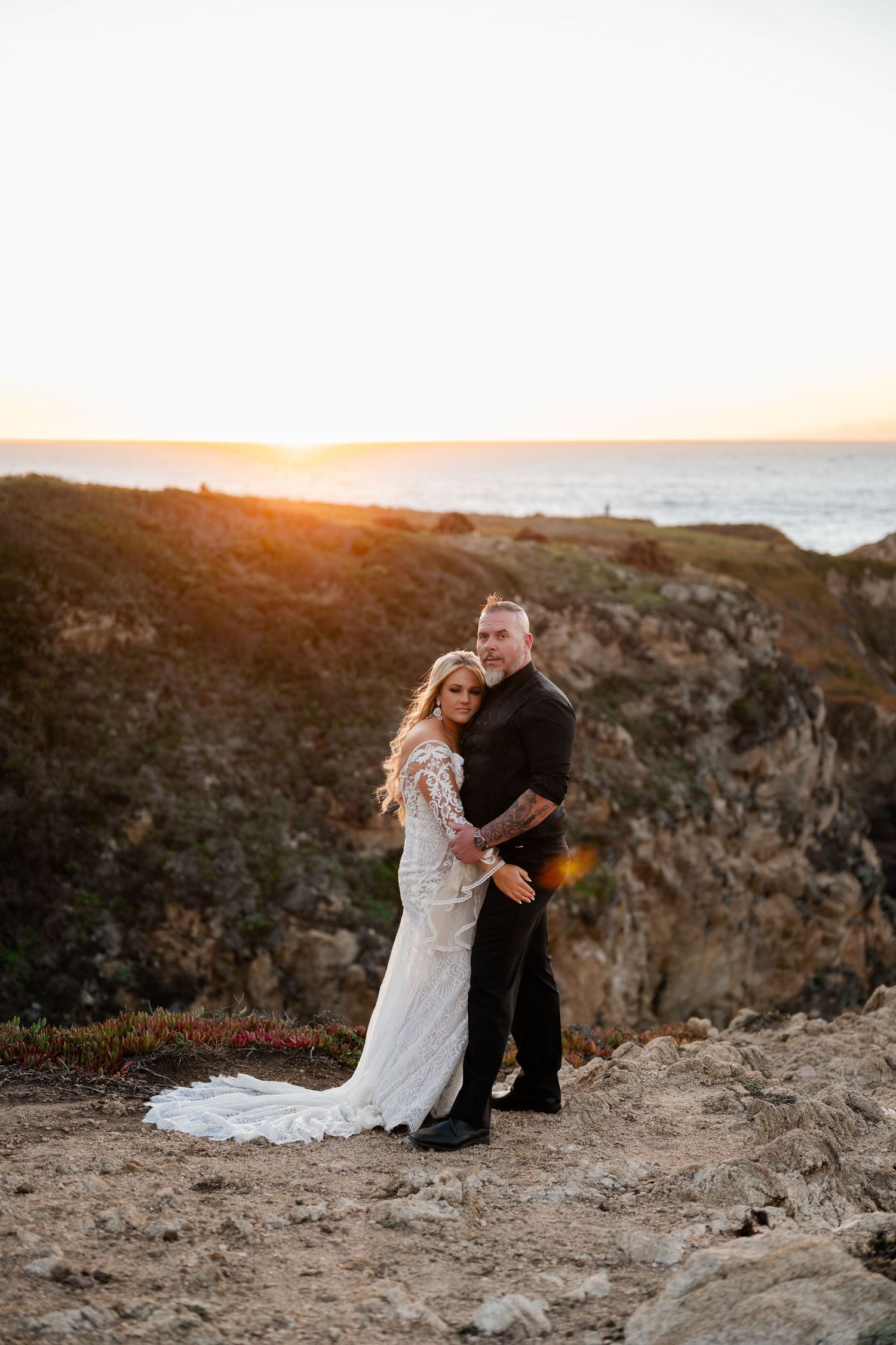A sunset wedding portrait on rugged coastal cliffs overlooking the ocean.
