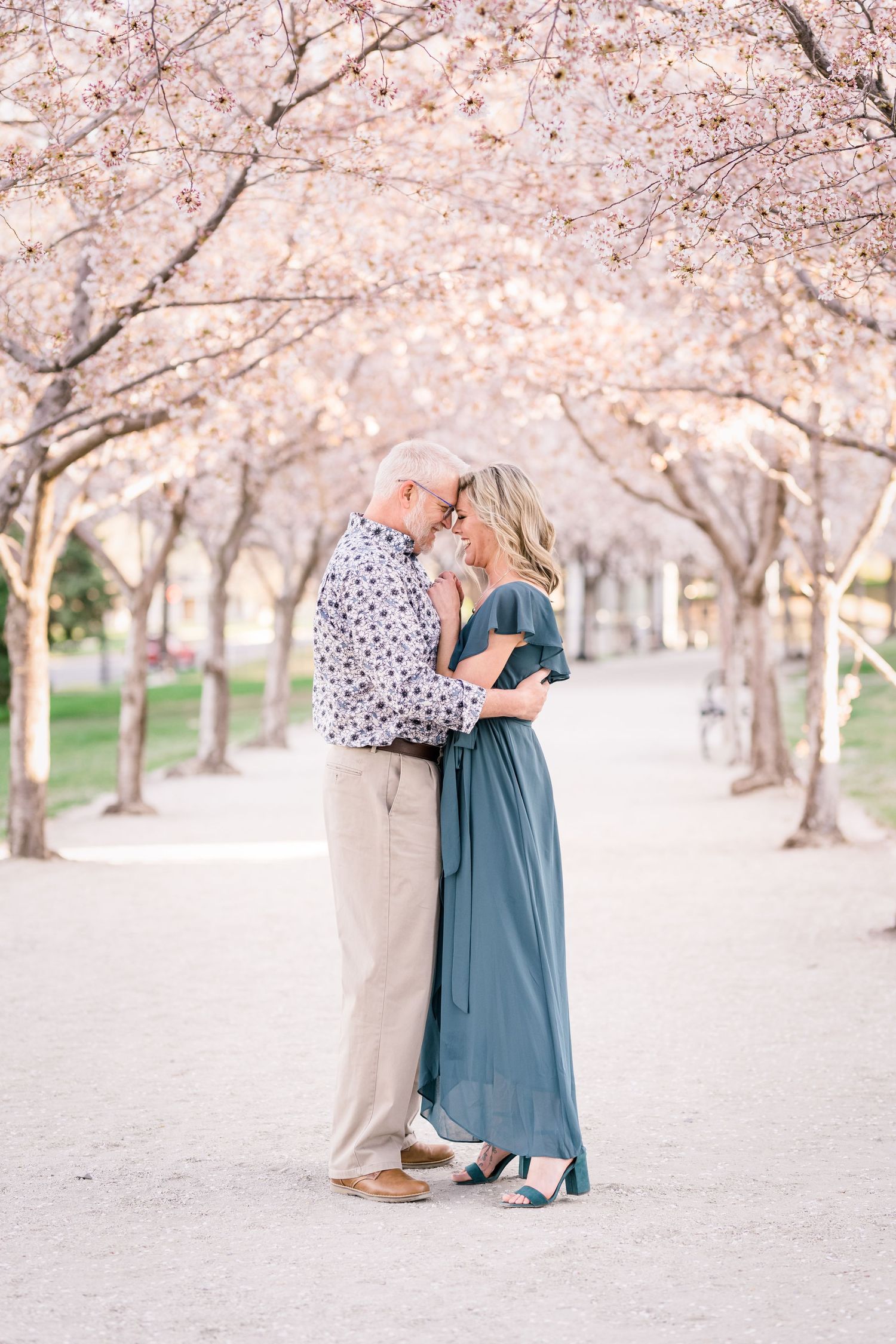 Engaged couple forehead to forehead under the blossoms at the Utah State Capitol by Utah Wedding photographer Coley Cook