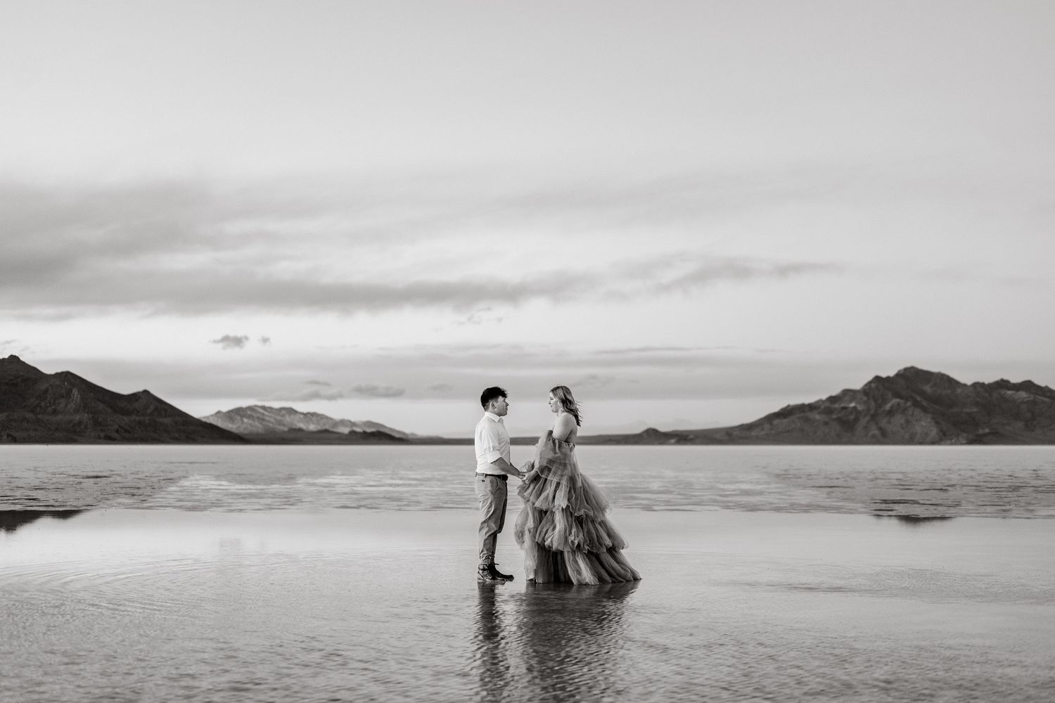 A couple holds hands as blue hour enhances the romance of a couple's photo session at the flooded Salt Flats.