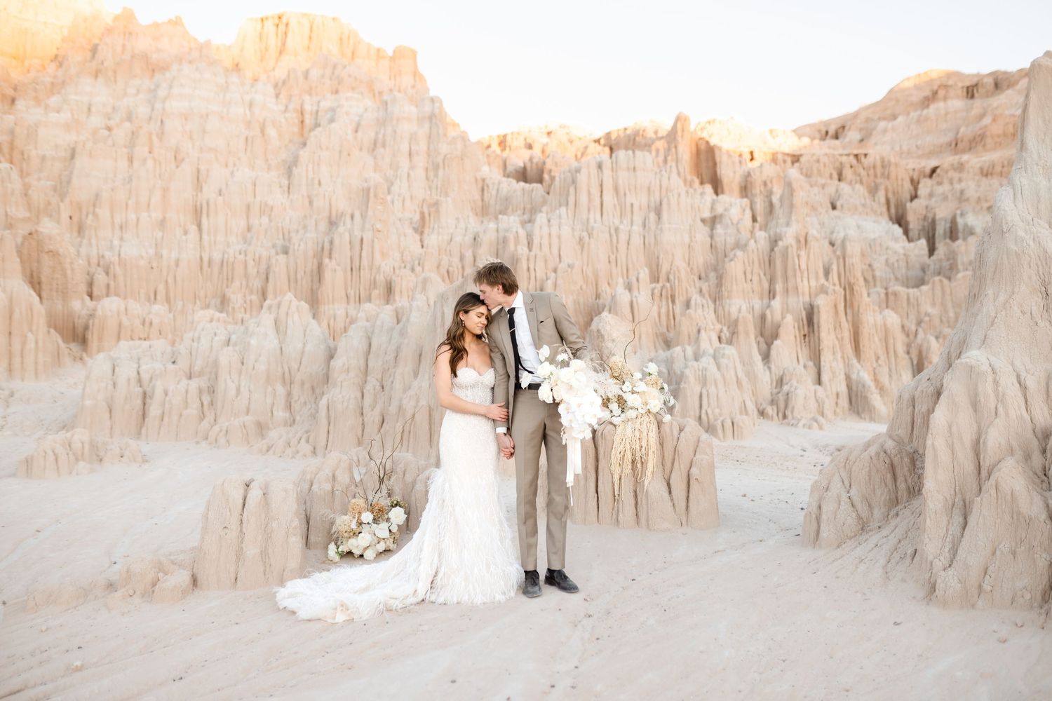 A bride in a flowing white wedding dress poses against stunning desert rock formations at Cathedral Gorge. Utah Wedding Photographer.