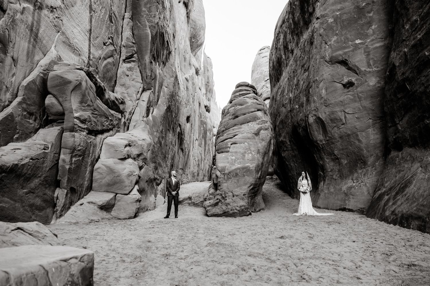 Wedding photos taken between towering red rock canyon walls in a dramatic desert landscape.