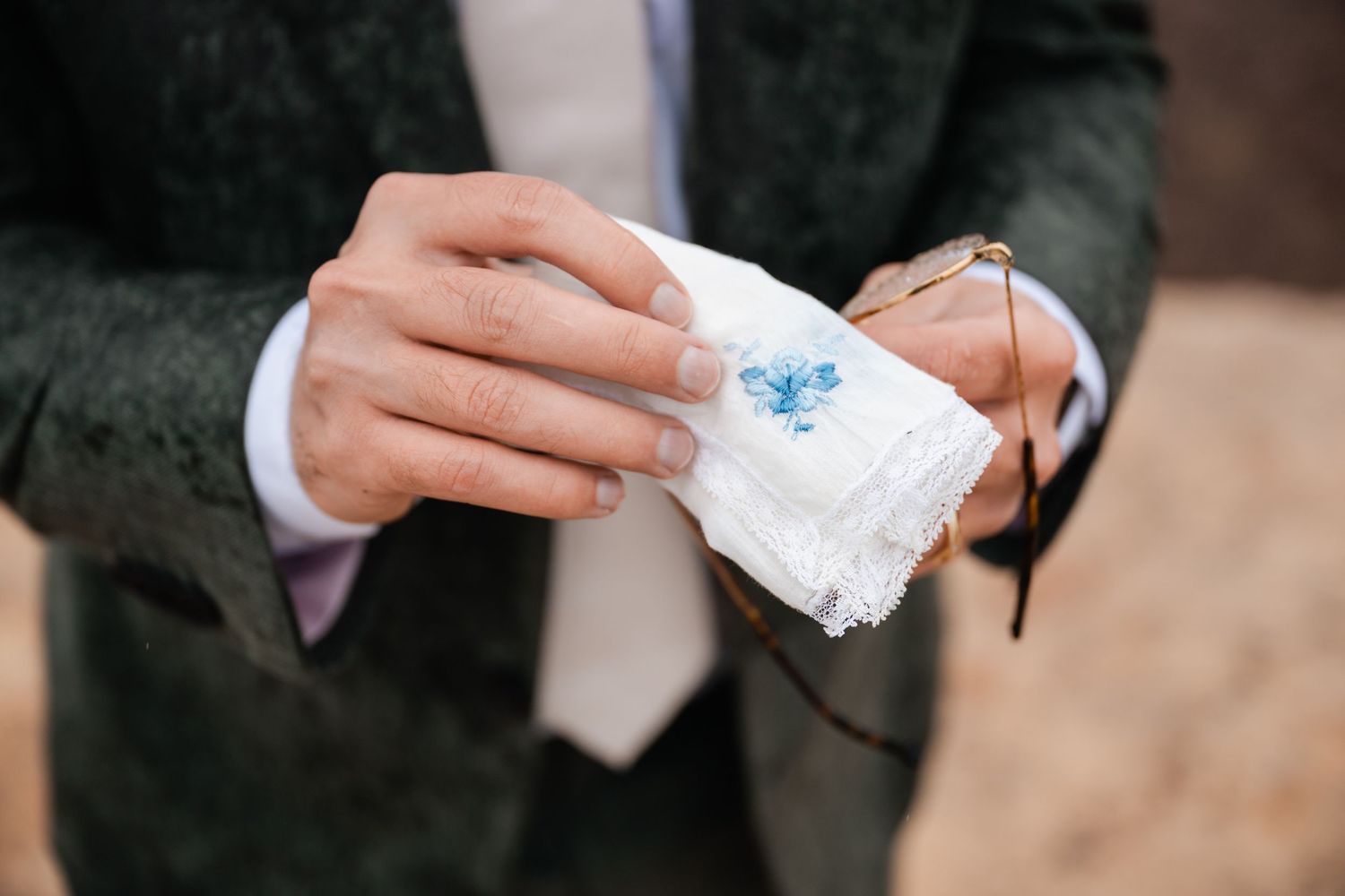 Hands hold delicate white lace fabric against a dark background.