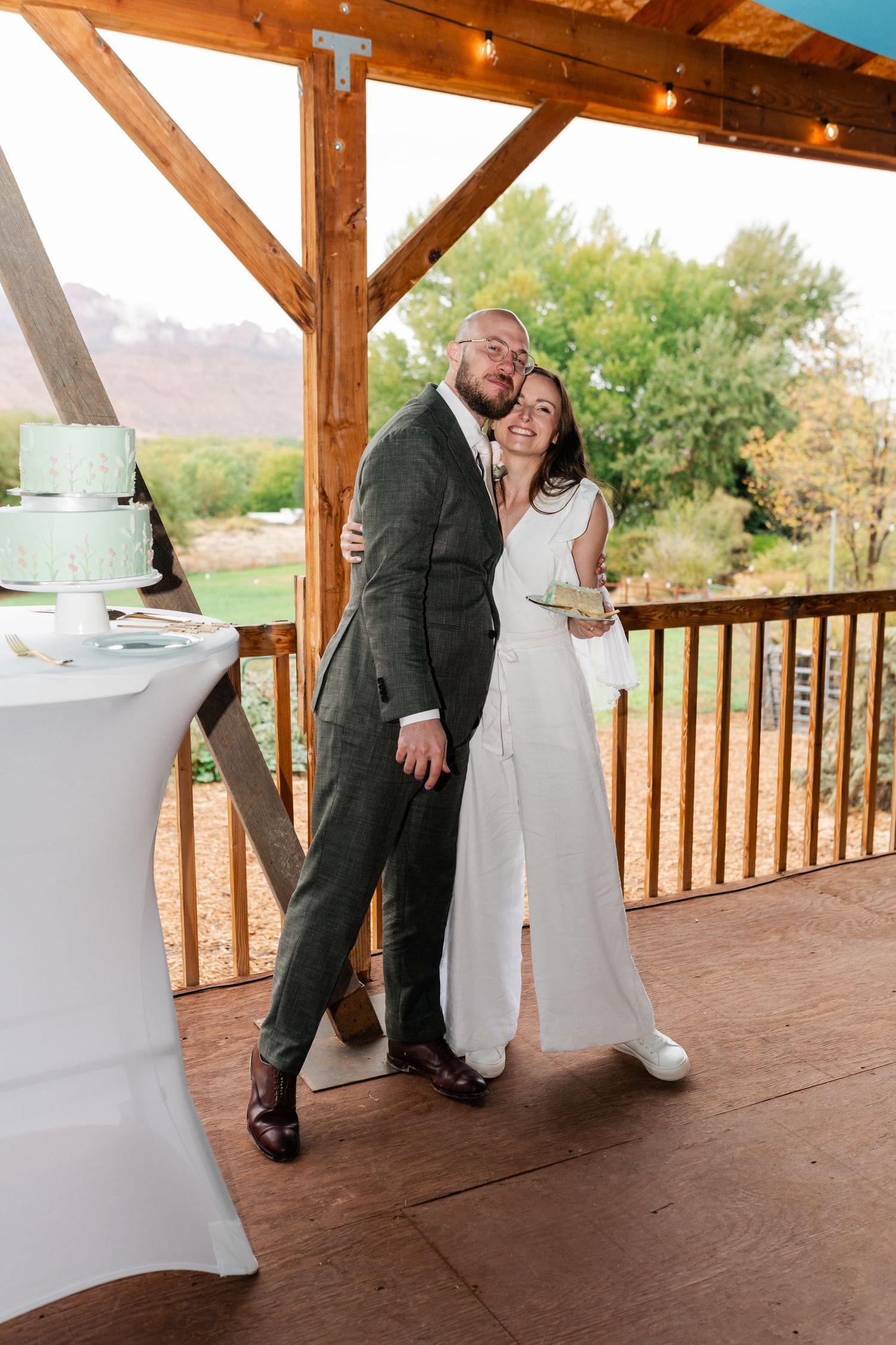 Couple shares a playful moment on a covered wooden deck during their wedding celebration.