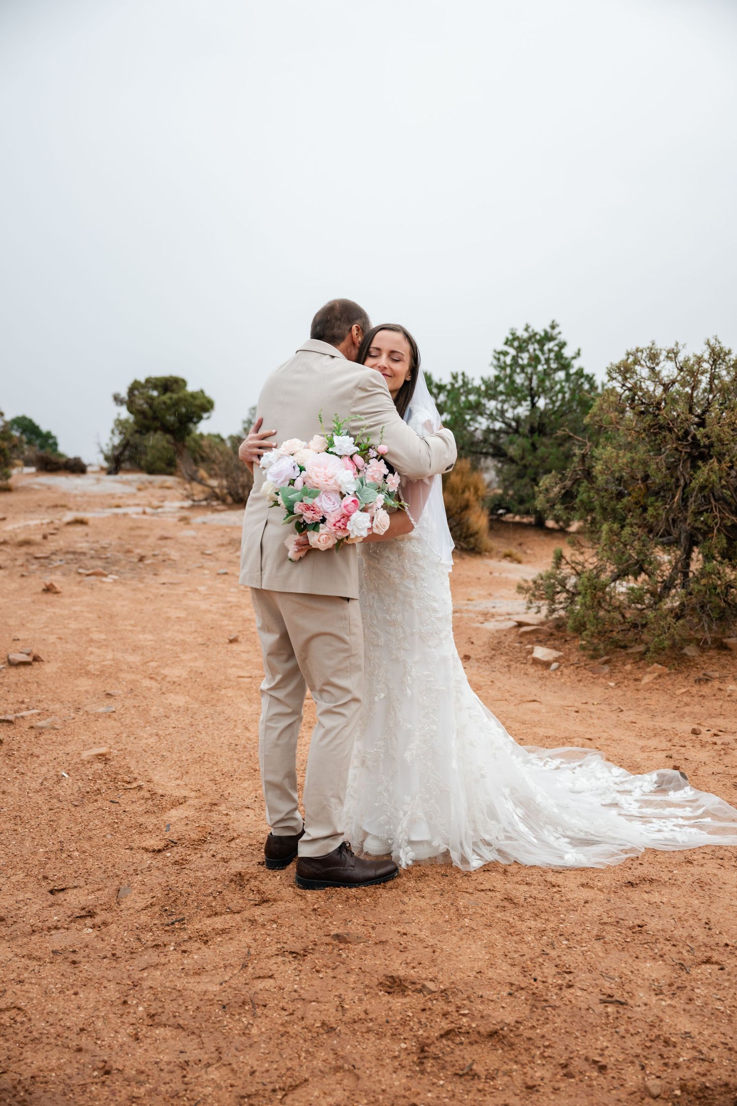 Intimate wedding ceremony on a desert cliff with a couple embracing in a romantic first look moment.