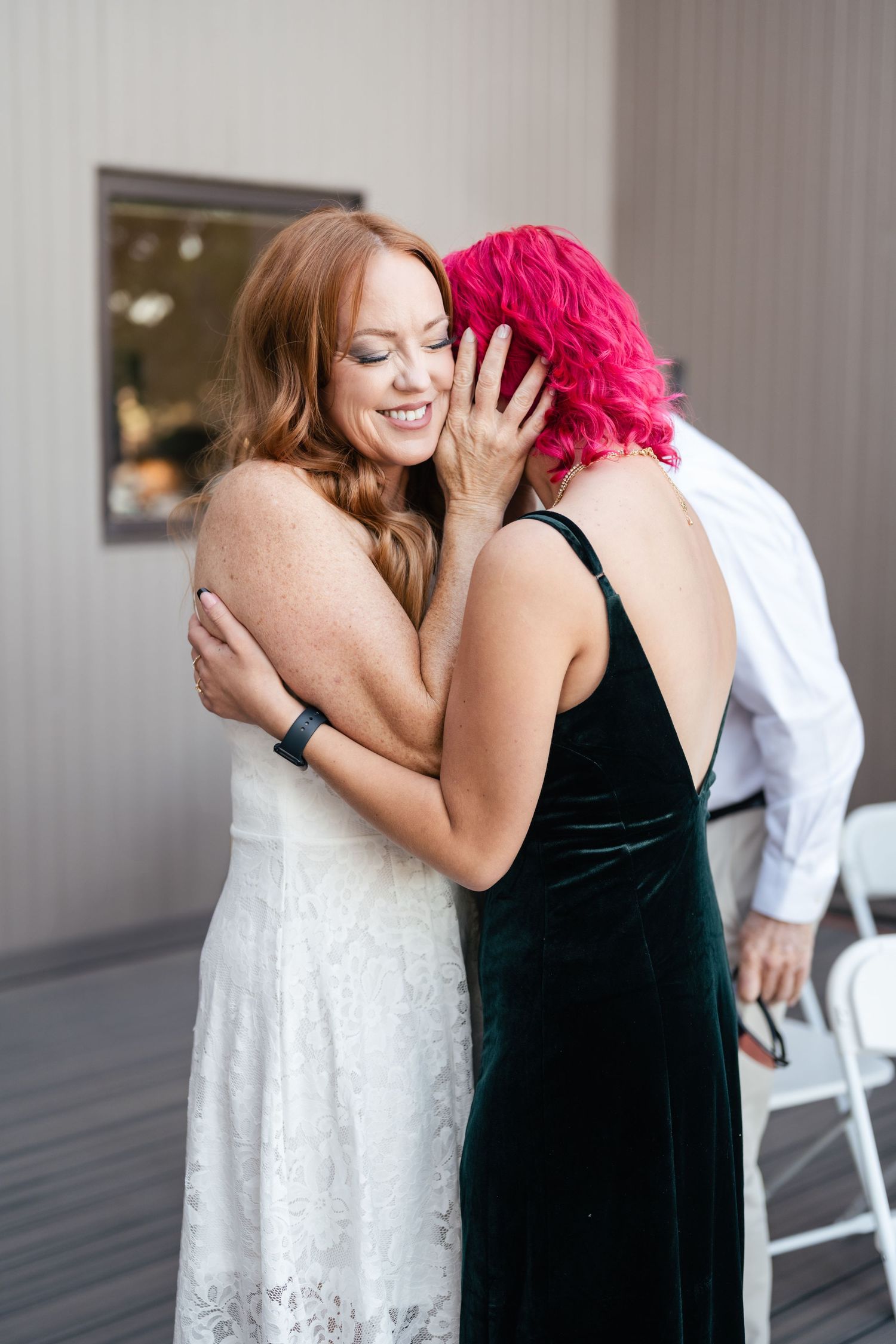Emotional embraces between wedding attendees wearing formal attire at an indoor celebration.