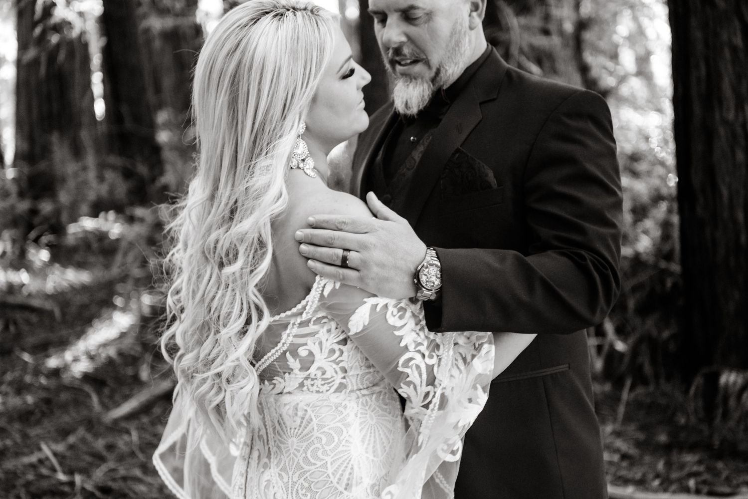 Romantic wedding moment captured in black and white against a dark background.